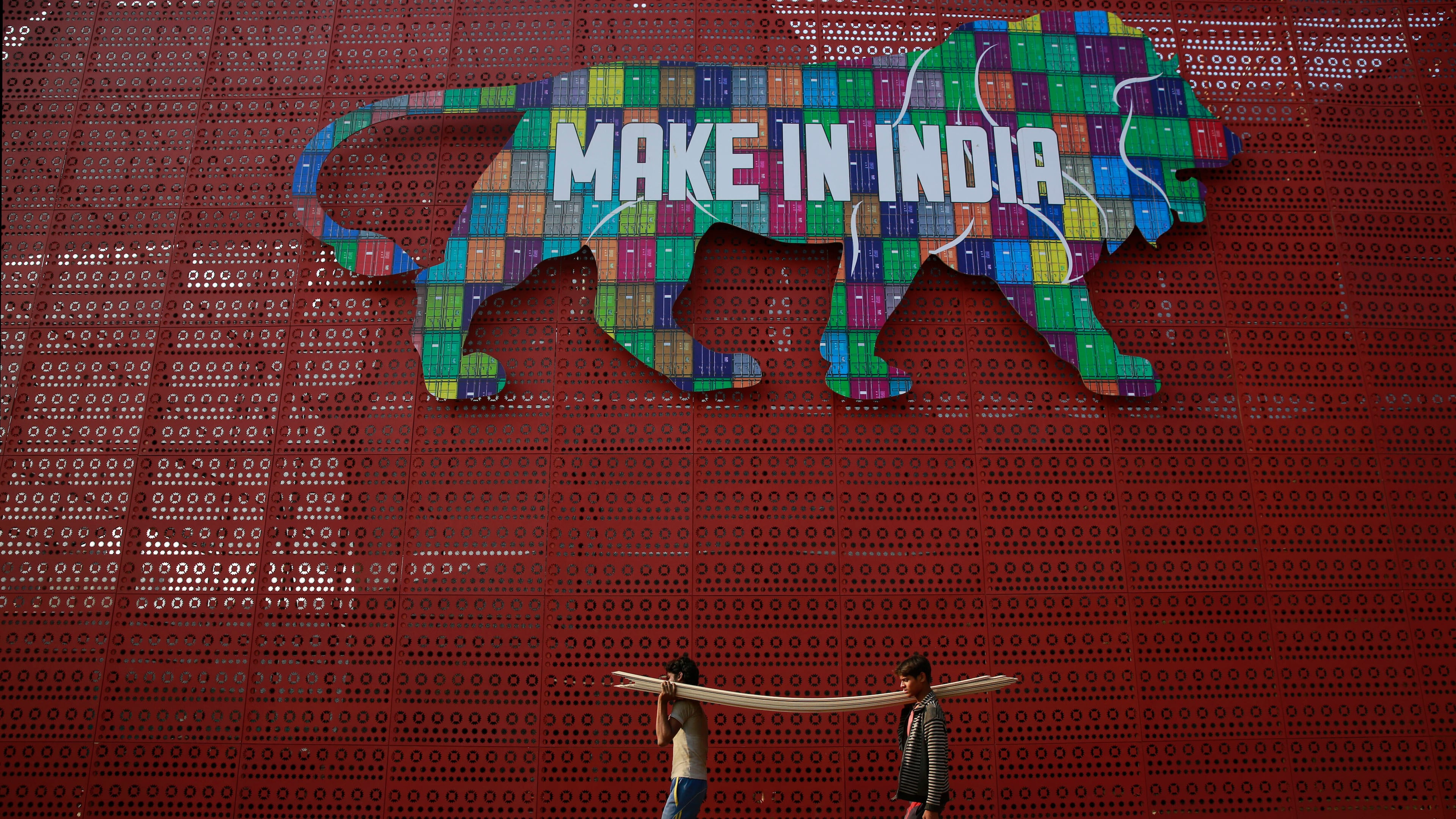 FILE - Laborers carry narrow planks of wood to be used for building a pavilion for the Make In India summit in Mumbai, India, Feb. 9, 2016. (AP Photo/Rafiq Maqbool, File)