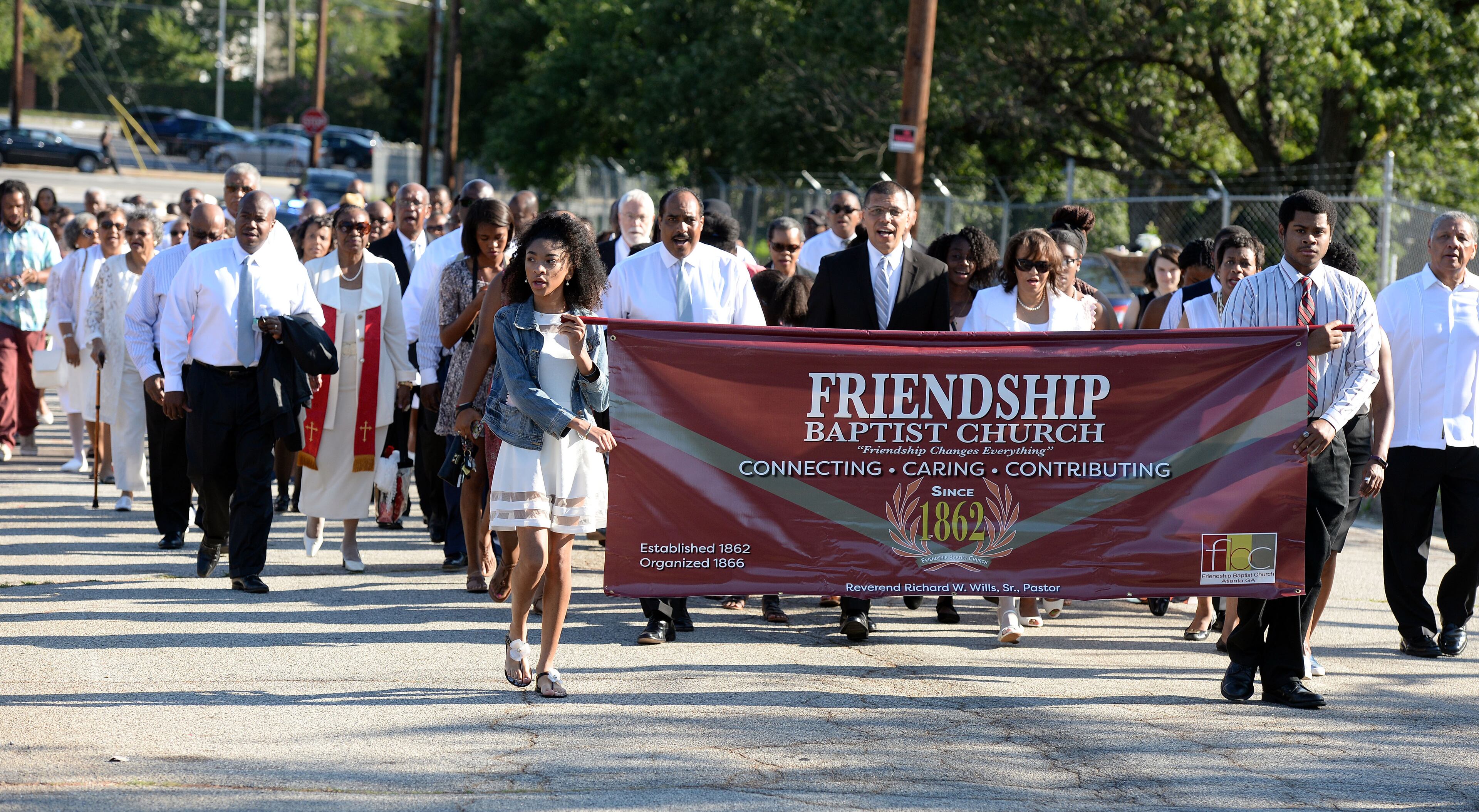 JULY 30, 2017 ATLANTA Morgan Jackson (left) and Renard Coleman, both 17, hold the banner as members march from the site of the old church to the new to attend the first morning worship service at Friendship Baptist Church Sunday, July 30, 2017. The 155-year old historic church, which started out as the home for both Morehouse and Spelman Colleges, was rebuilt after their former building was demolished to make way for the Falcons' Mercedes-Benz Stadium. KENT D. JOHNSON / AJC