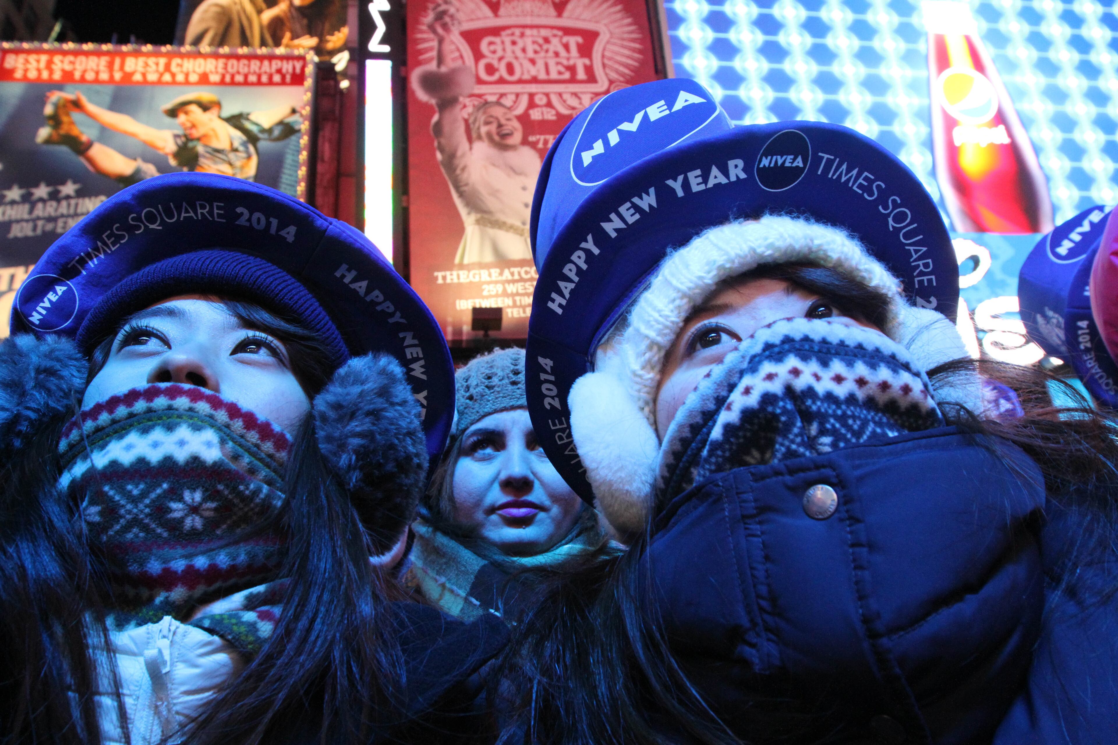 Bundled against the cold, Yuri Asano, left, and her sister Mami Asano, right, both from Aichi, Japan, take part in the New Year's Eve festivities Tuesday Dec. 31, 2013 in New York's Times Square. (AP Photo/Tina Fineberg)