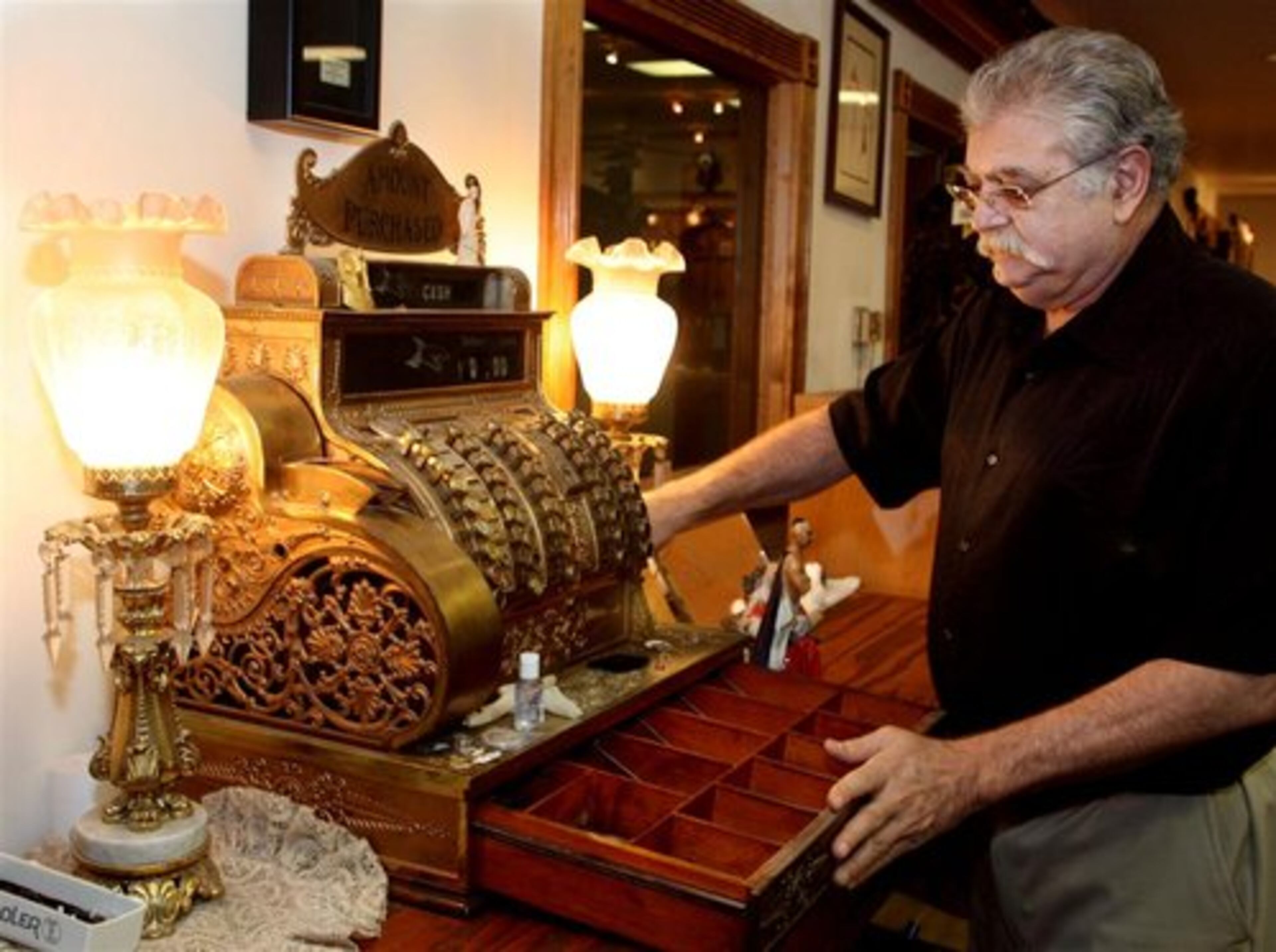 Joe Ellis, owner of Cherokee Coin and Pawn in Alpharetta, operates an 1898 cash register that he's used for many years. His company is one of the largest and most respected dealers of coins, but he also operates a high-end pawn business. He said the economic downturn has increased the number of people looking for short-term loans.