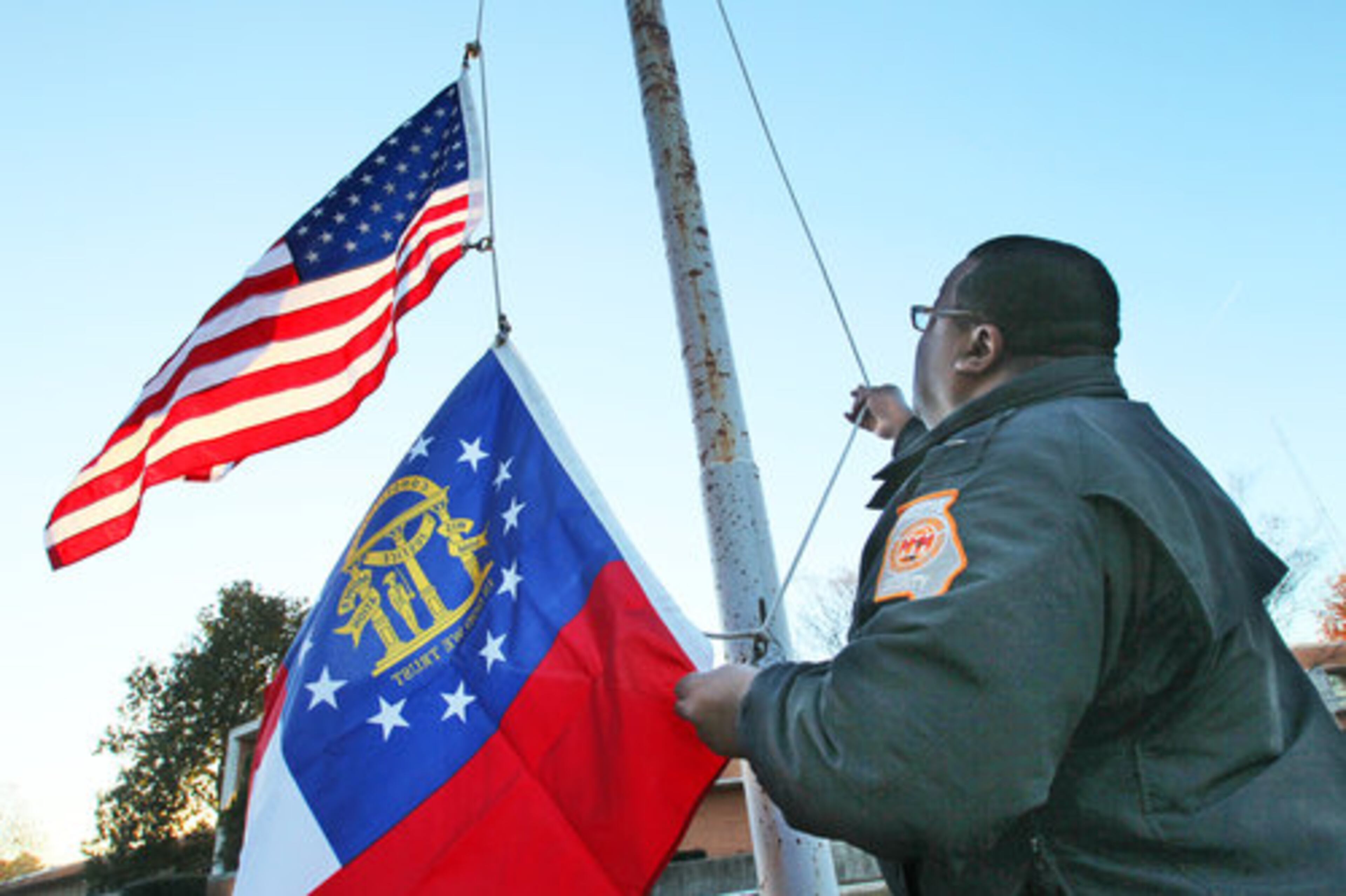 Capitol Police Sgt. Anthony Hughes raises the flags to half-staff Tuesday, Dec. 28, 2010 at the Department of Public Safety Headquarters at 959 E. Confederate Avenue in Atlanta after the death of Trooper Chadwick LeCroy, 38, of Marietta who was slain by a suspect he had tried to pull over Monday night.