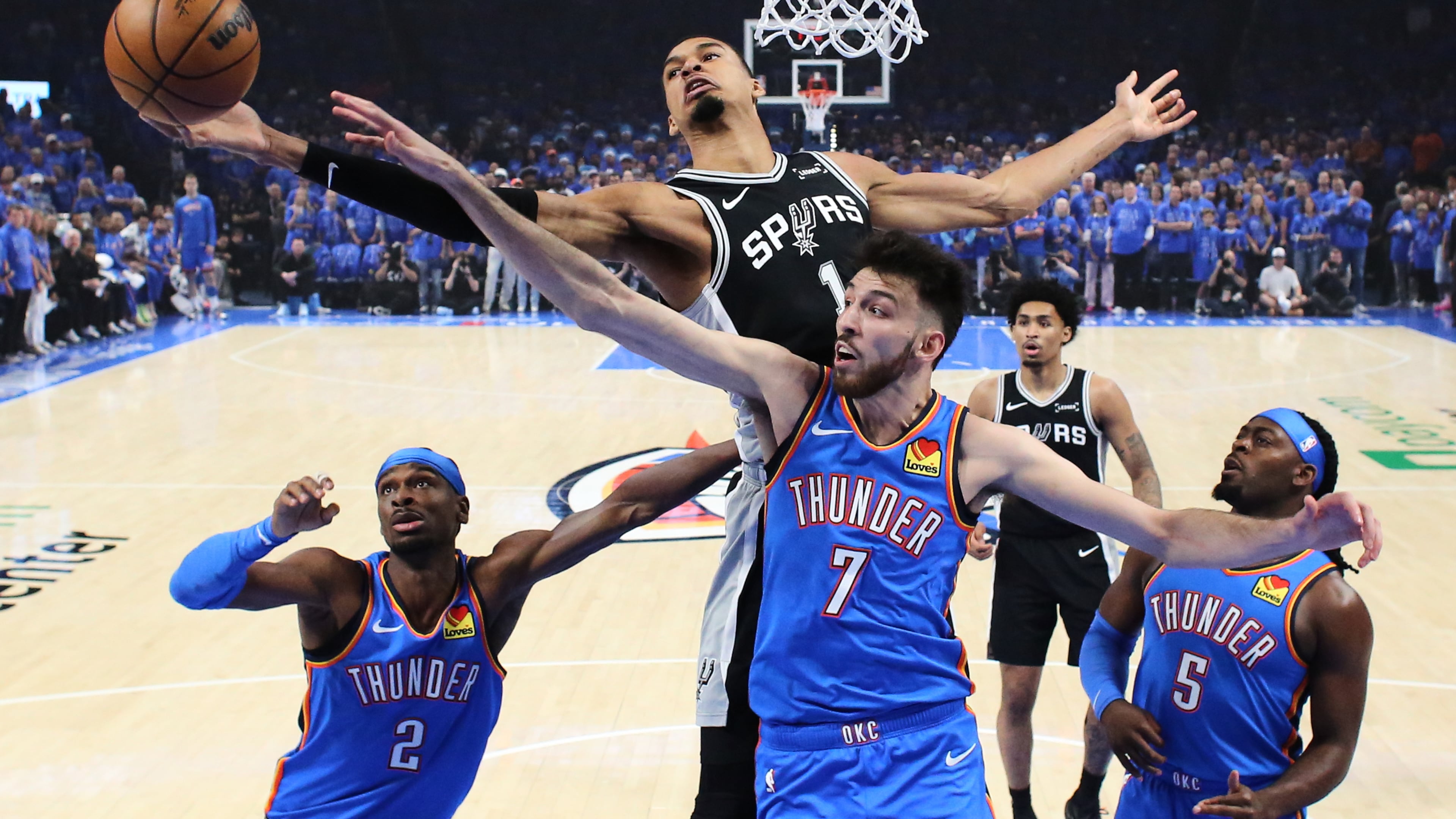 San Antonio Spurs forward Victor Wembanyama (1) and Oklahoma City Thunder center Chet Holmgren (7) reach for a rebound during the first half of Game 1 in a third-round NBA basketball playoffs series Monday, May 18, 2026, in Oklahoma City. (AP Photo/Nate Billings)