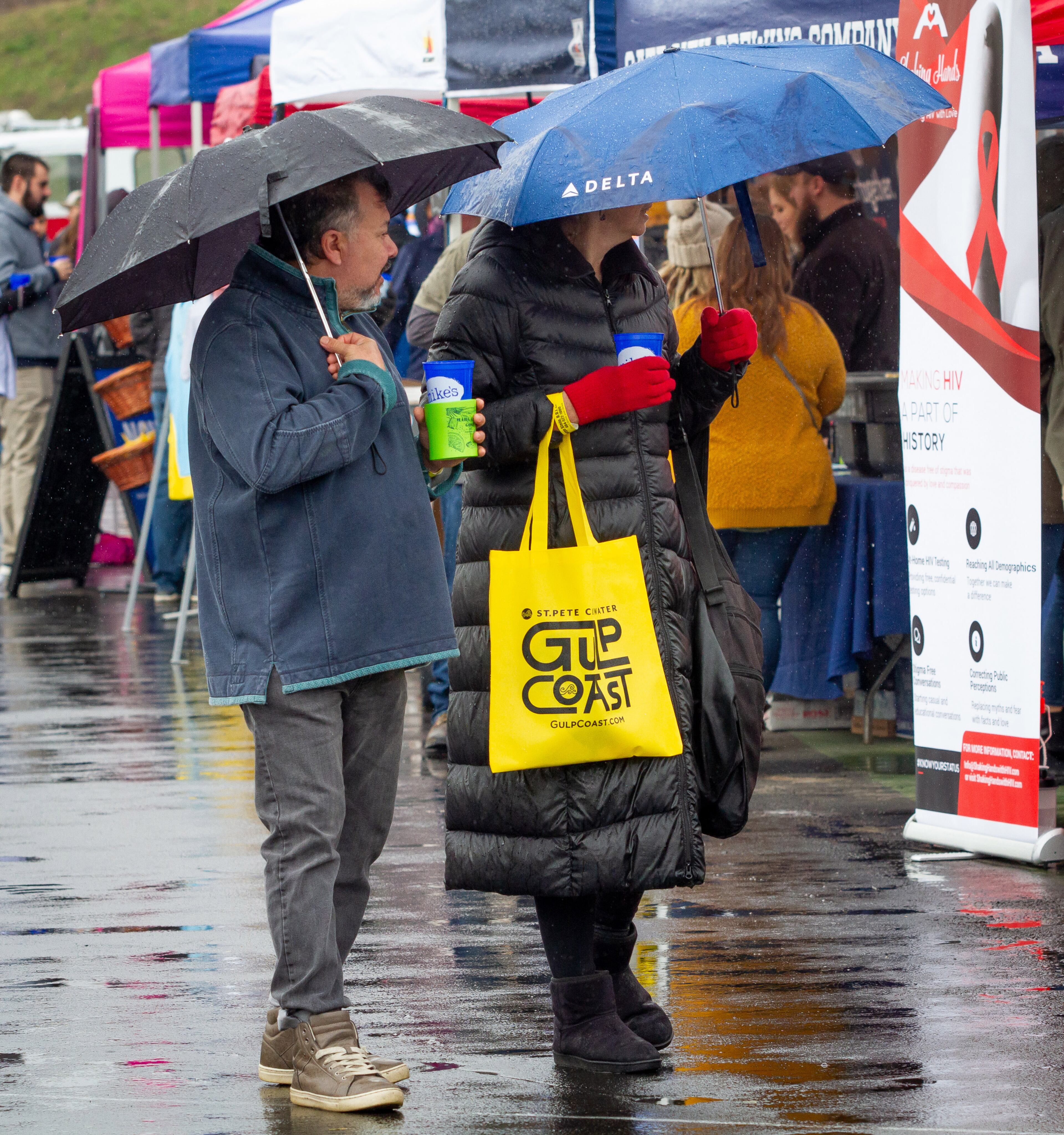Javier Campos and Alicia Cuneo try to stay dry during a brief rain shower at the Atlanta Winter Beer Festival at Atlantic Station on Saturday, February 1, 2020. STEVE SCHAEFER / SPECIAL TO THE AJC