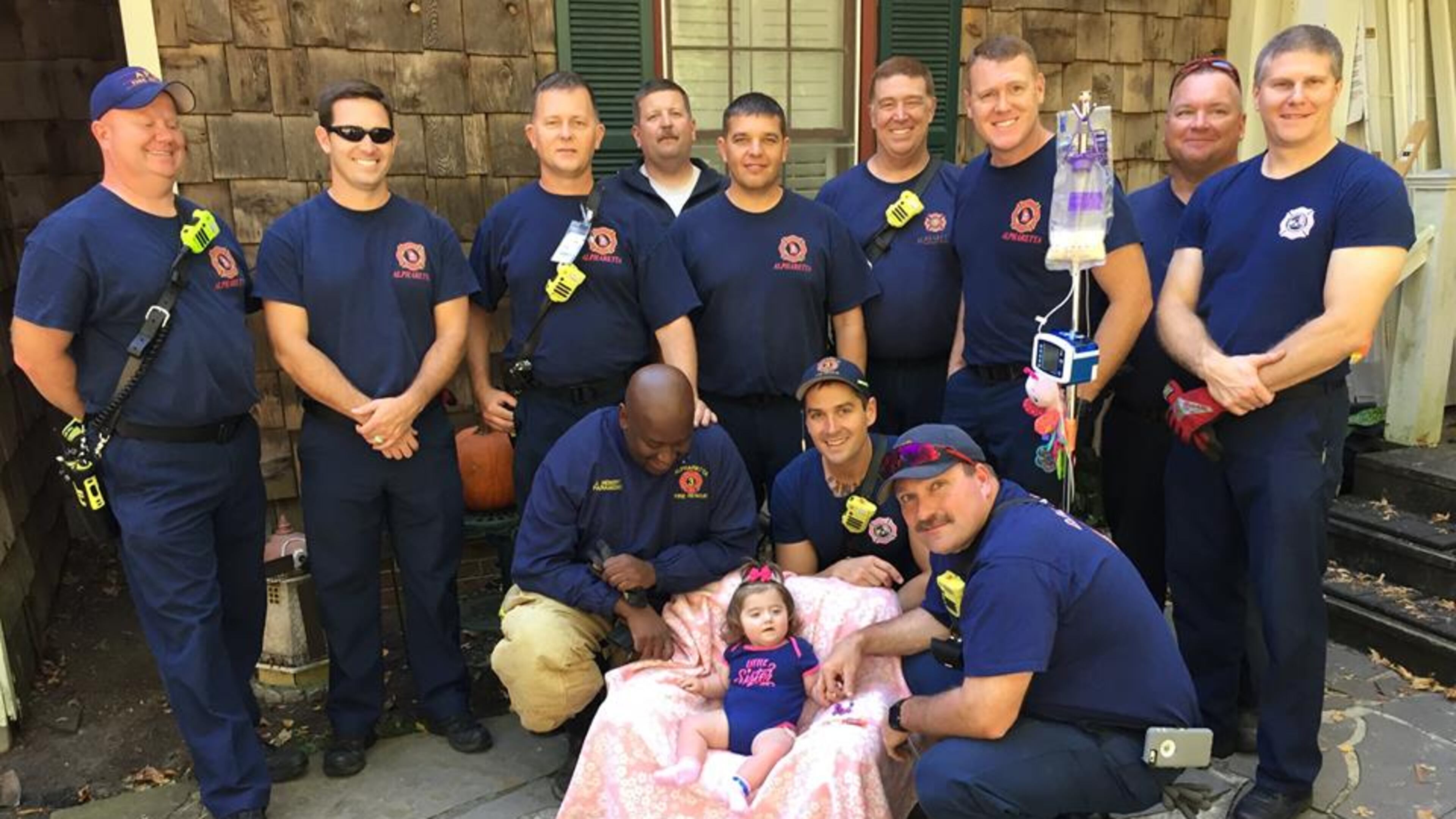 Multiple members of the Alpharetta Fire Department surround 11-month-old Raven Nell Raines outside of her home on Sherry Lane.