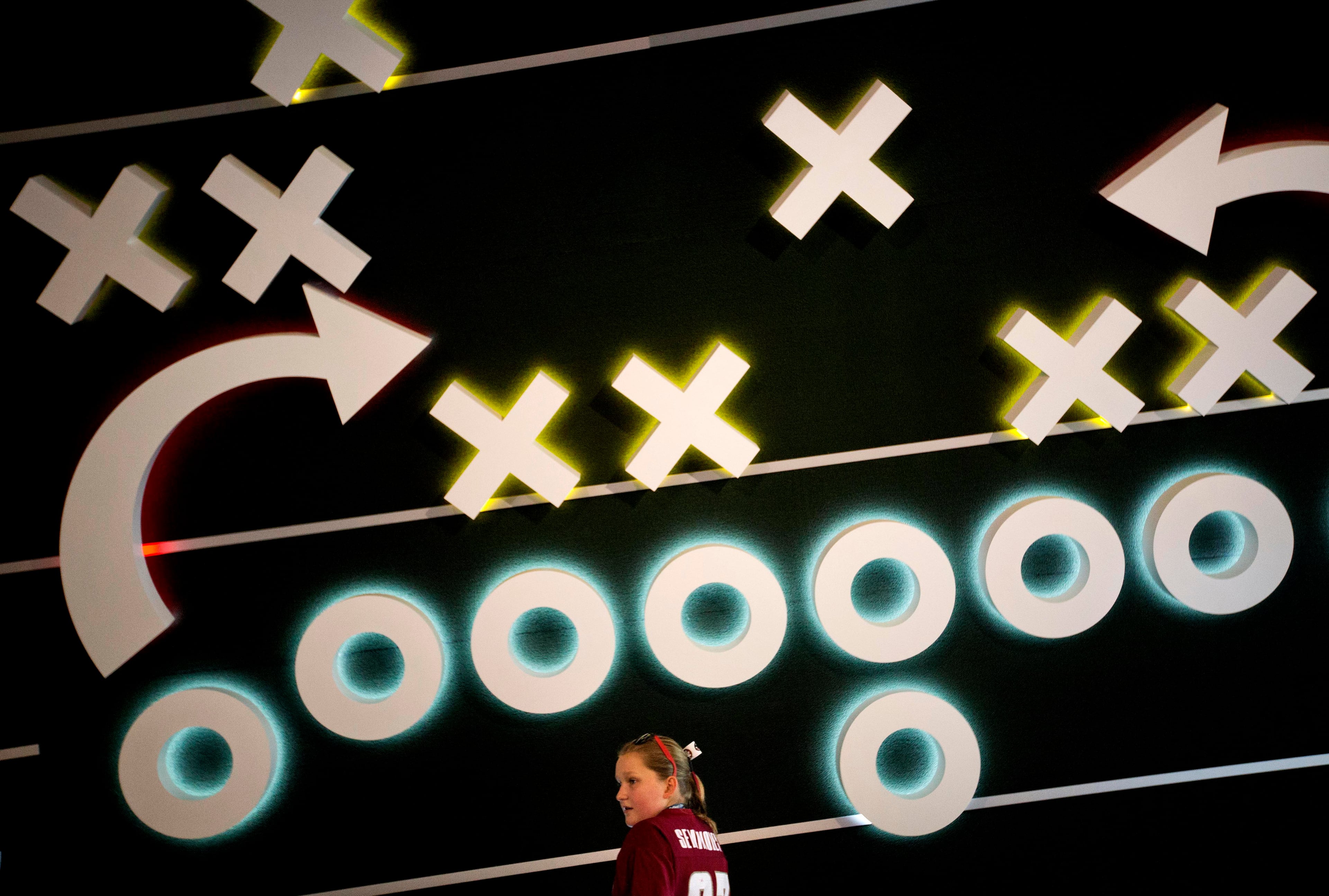 Klava Johnson, 12, of Dunwoody, Ga., stands in front of an interactive exhibit while touring the College Football Hall of Fame, Wednesday, Aug. 13, 2014, in Atlanta. Exhibits incuding a coaching video tutorial help explain how a play is constructed by well known head coaches and even allows visitors to flip through the playbook John Heisman used in the 1920s. (AP Photo/David Goldman)