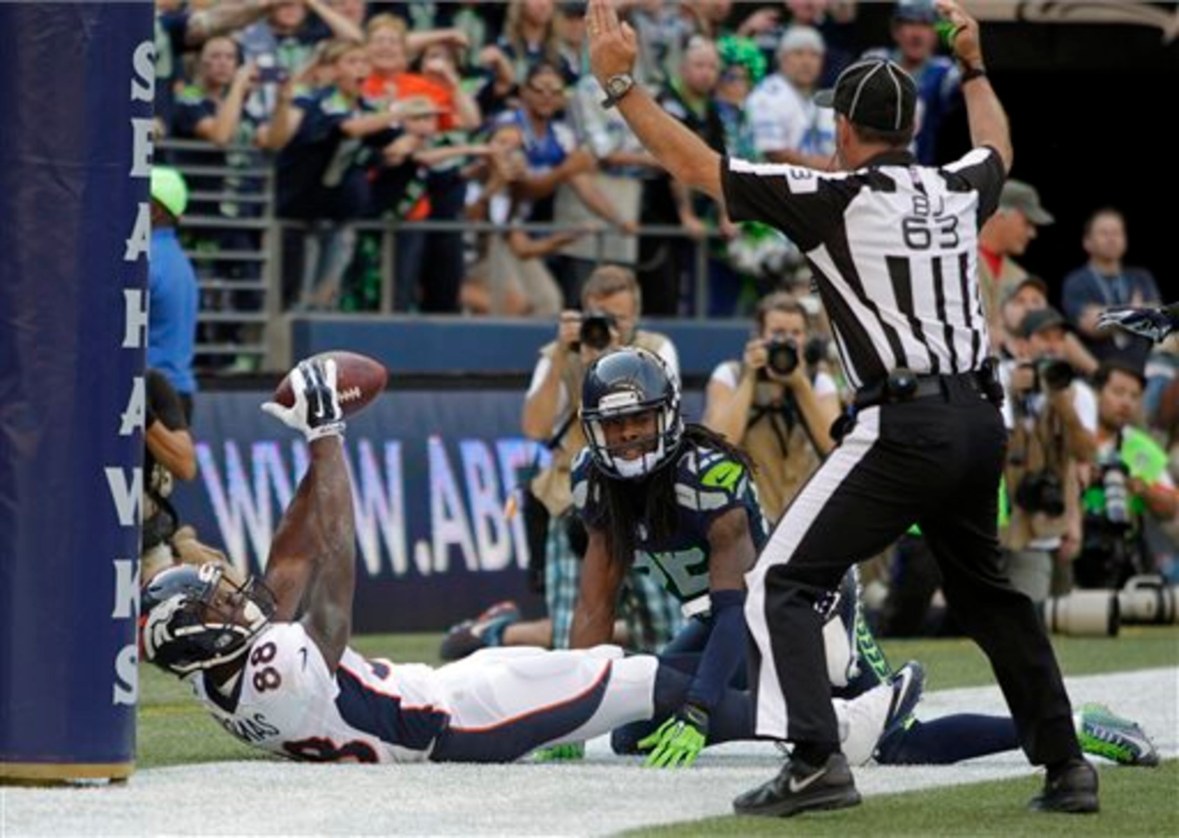 Denver Broncos wide receiver Demaryius Thomas (88) scores a game-tying 2-point conversion as Seattle Seahawks cornerback Richard Sherman watches and back judge Jim Quirk makes the call in the second half of an NFL football game, Sunday, Sept. 21, 2014, in Seattle. (AP Photo/John Froschauer)