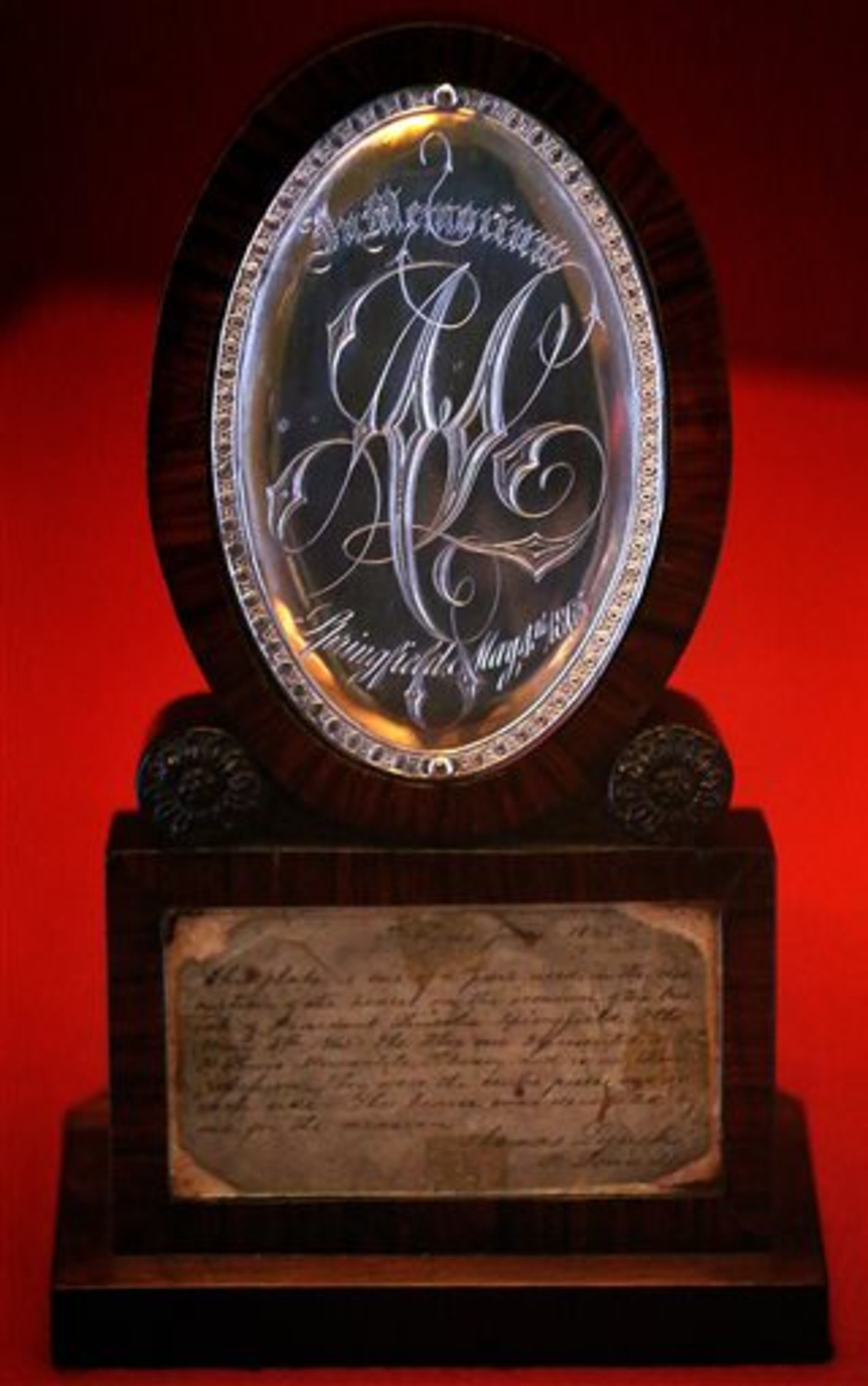 In this Thursday, April 2, 2015 photo, one of two silver medallions from the hearse that carried Abraham Lincoln to his grave are on display at the Abraham Lincoln Presidential Museum in Springfield, Ill. The elaborate gothic script on the medallion reads: In Memoriam A.L. Springfield May 4th 1865. The new exhibit �A Fiendish Assassination�, opened in the Treasures Gallery at the Museum Thursday, and runs until early July. The more than 40 artifacts displayed-many never before seen in public show items related to Lincoln�s death and funeral 150 years ago this year. (AP Photo/The State Journal-Register, David Spencer)