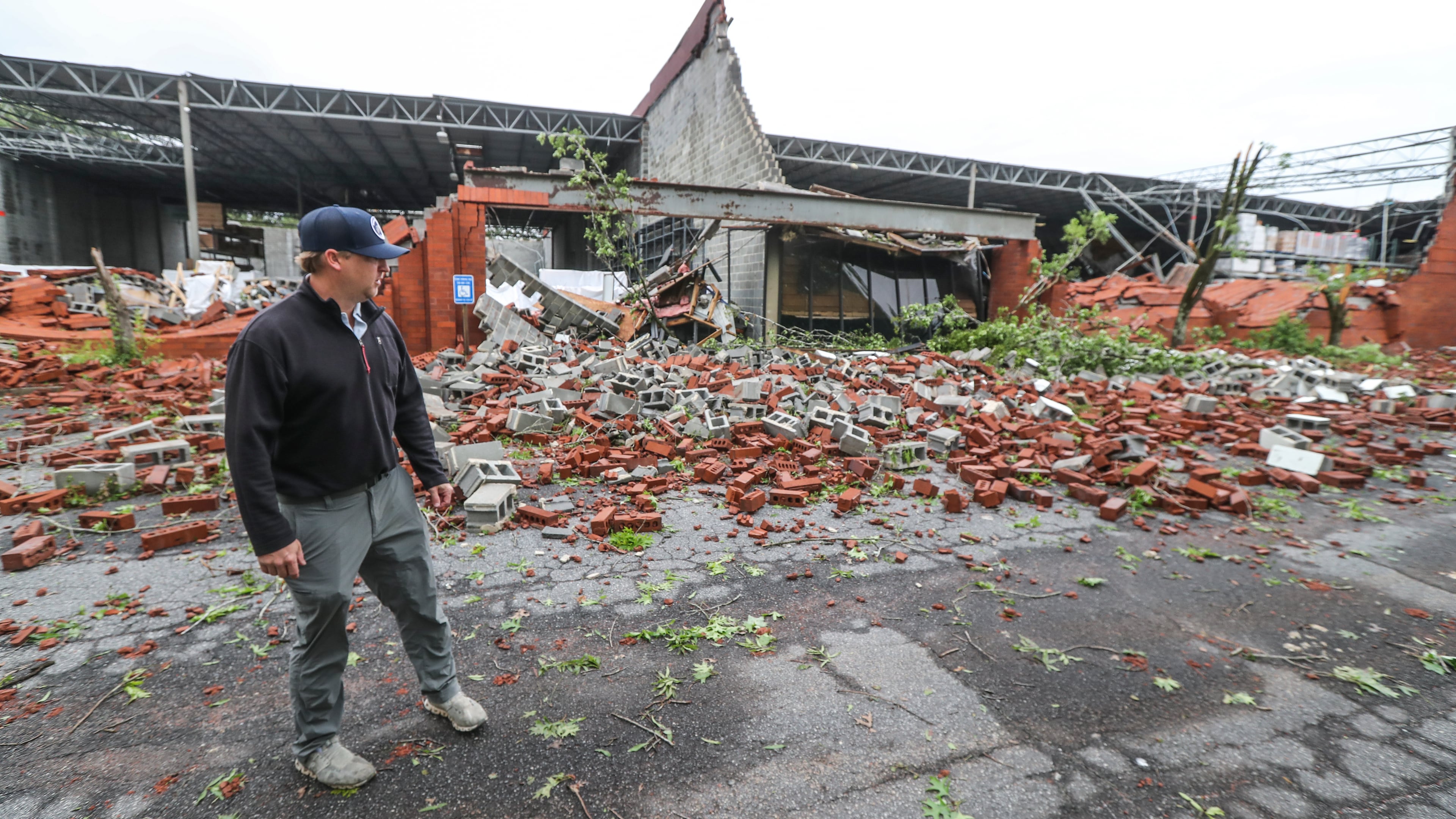 Dru Ghegan surveys the damage to his Fulton County business Tuesday after a severe storm rolled through the area.