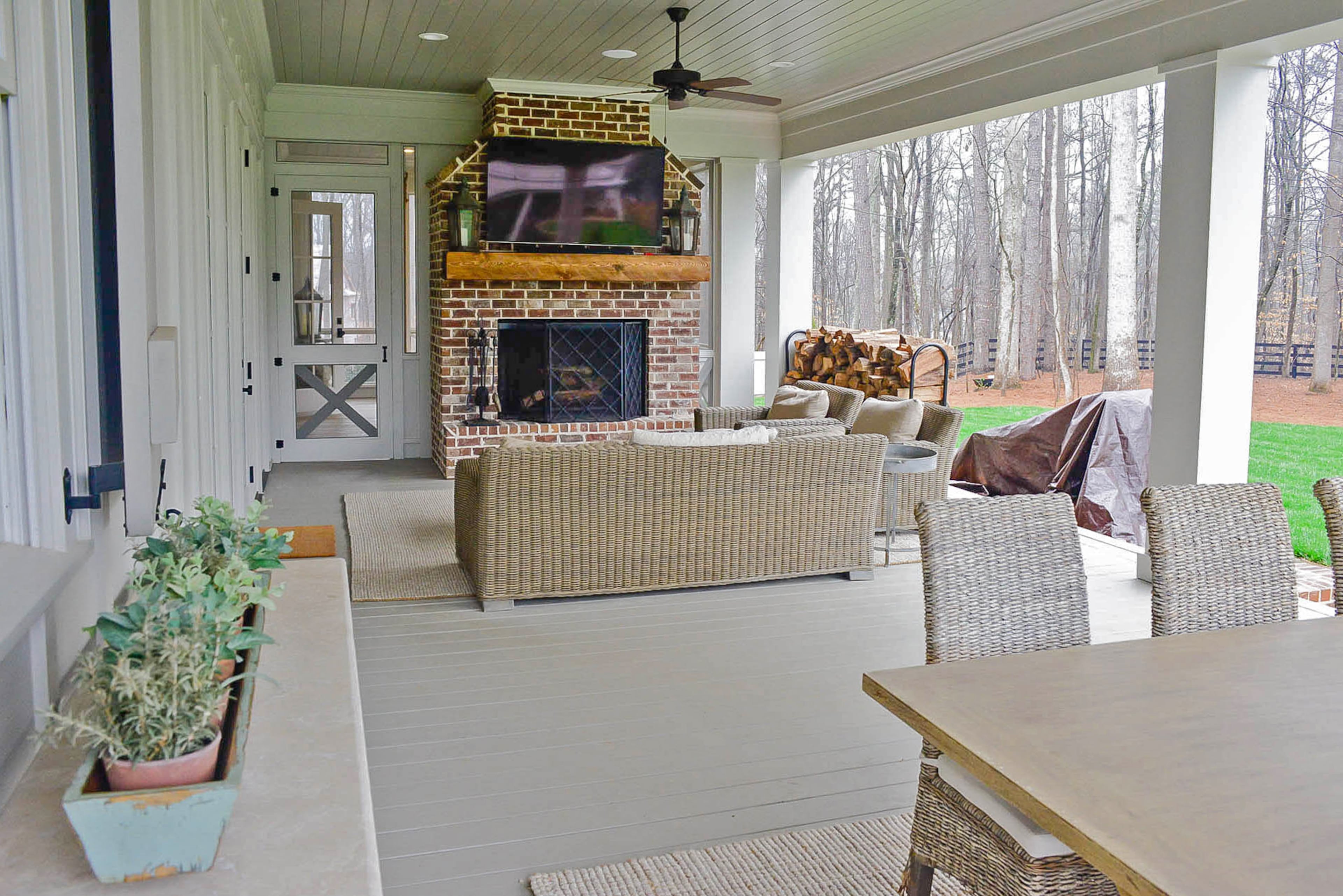 The covered back porch of the Canton residence contains both a dining area and entertaining area with a fireplace and TV.