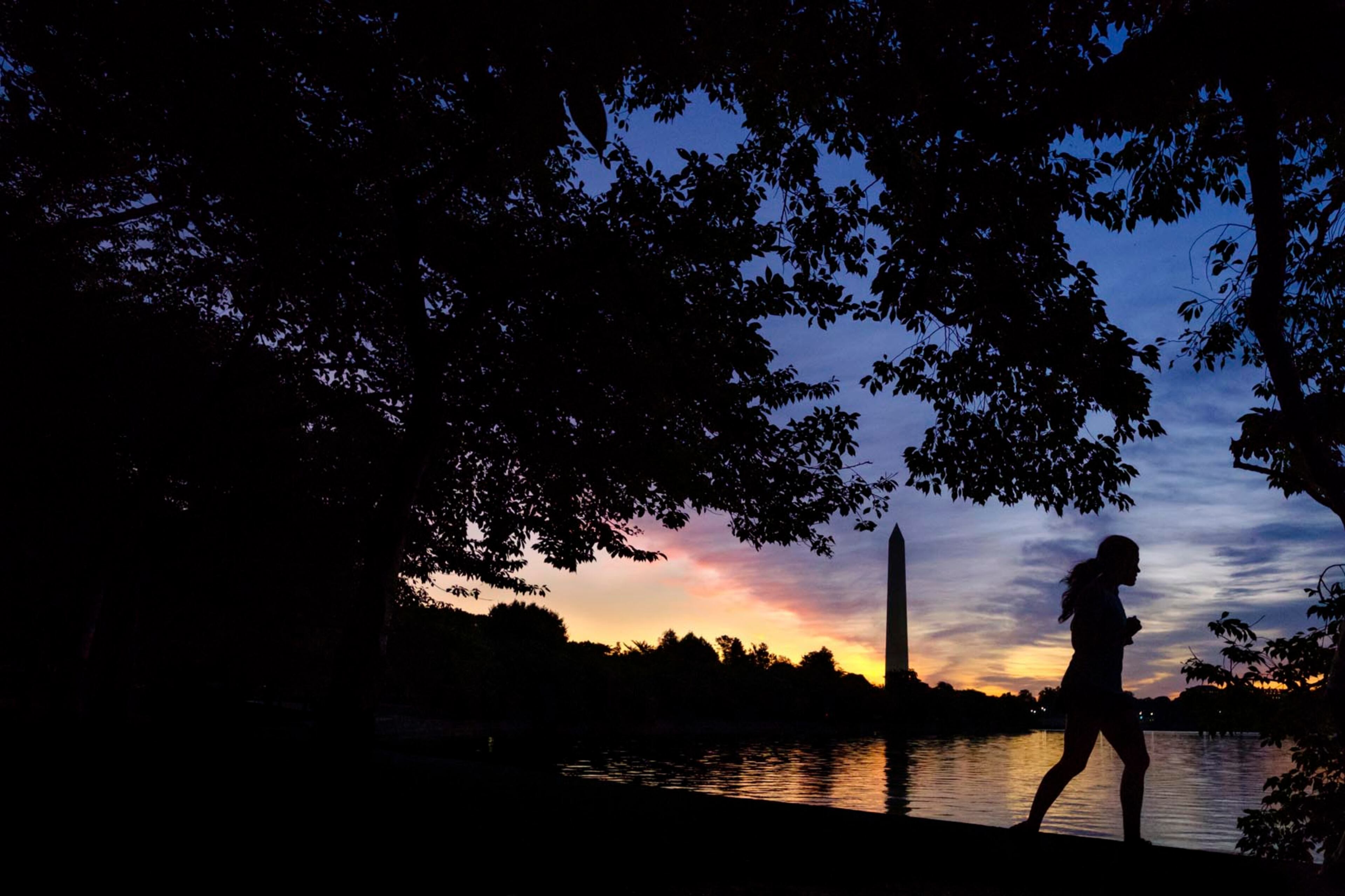 An early morning runner is silhouetted against the rising sun at the Tidal Basin in Washington, Tuesday, July 25, 2017. (AP Photo/J. David Ake)