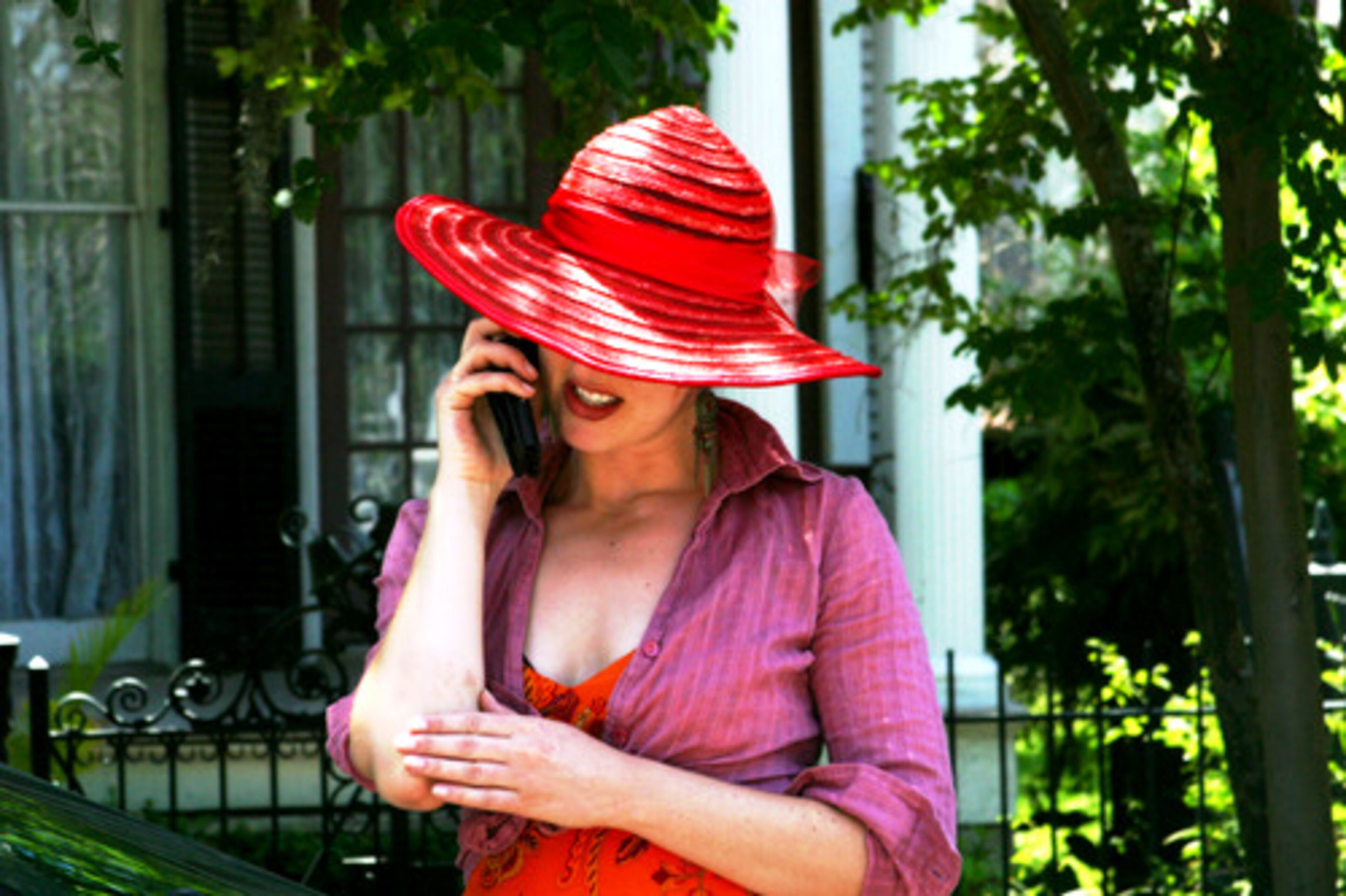 New Orleans Jazz & Heritage Festival, 4/29/2007, A girl shaded by a red hat listens intently to her cellphone during Jazz Fest.