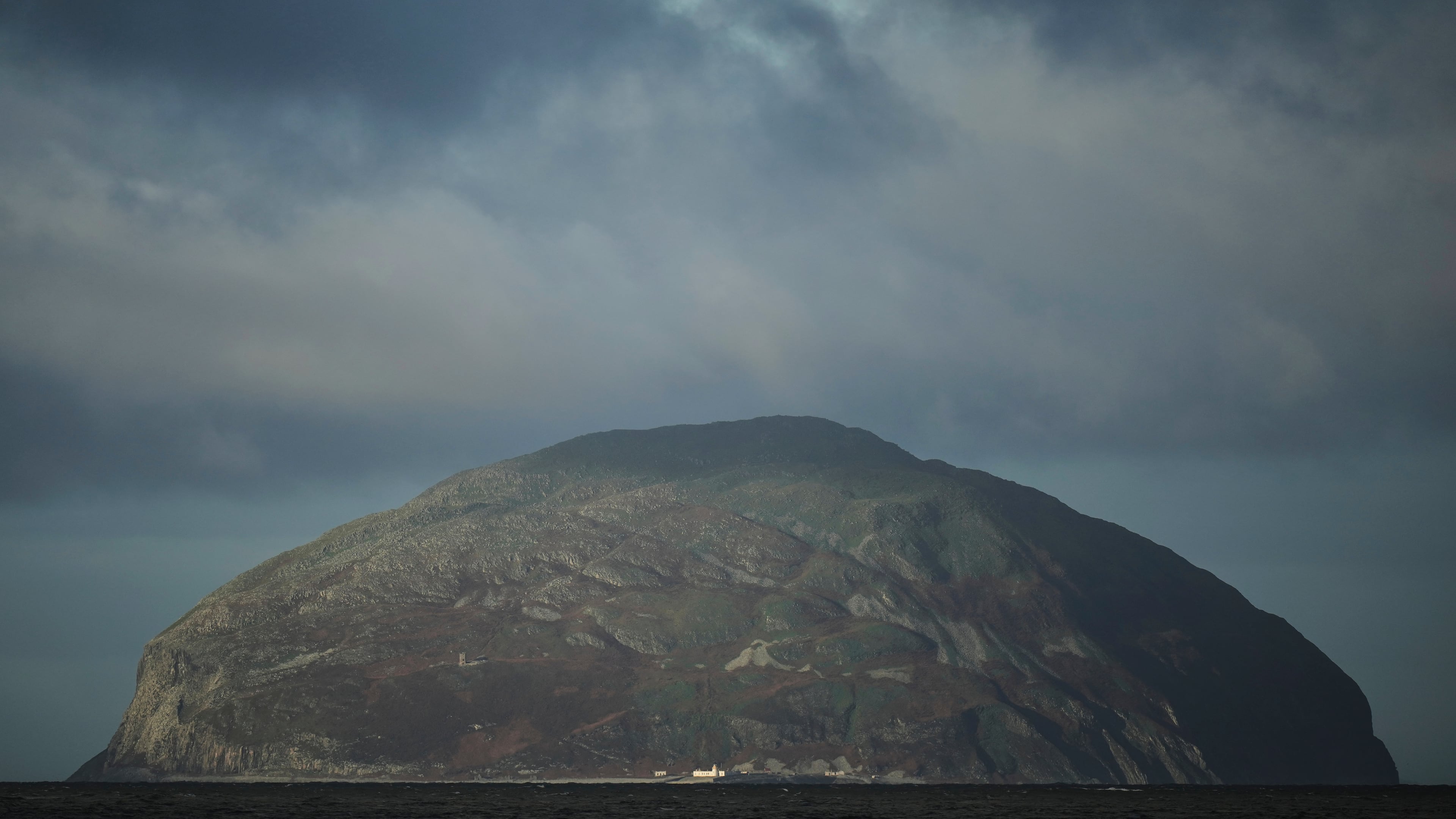 The island of Ailsa Craig, where the two types of granite, Common Green and Blue Hone, that are used to make curling stones is quarried from, is seen from the beach at Girvan, Scotland, Thursday, Nov. 13, 2025. (AP Photo/Alastair Grant)