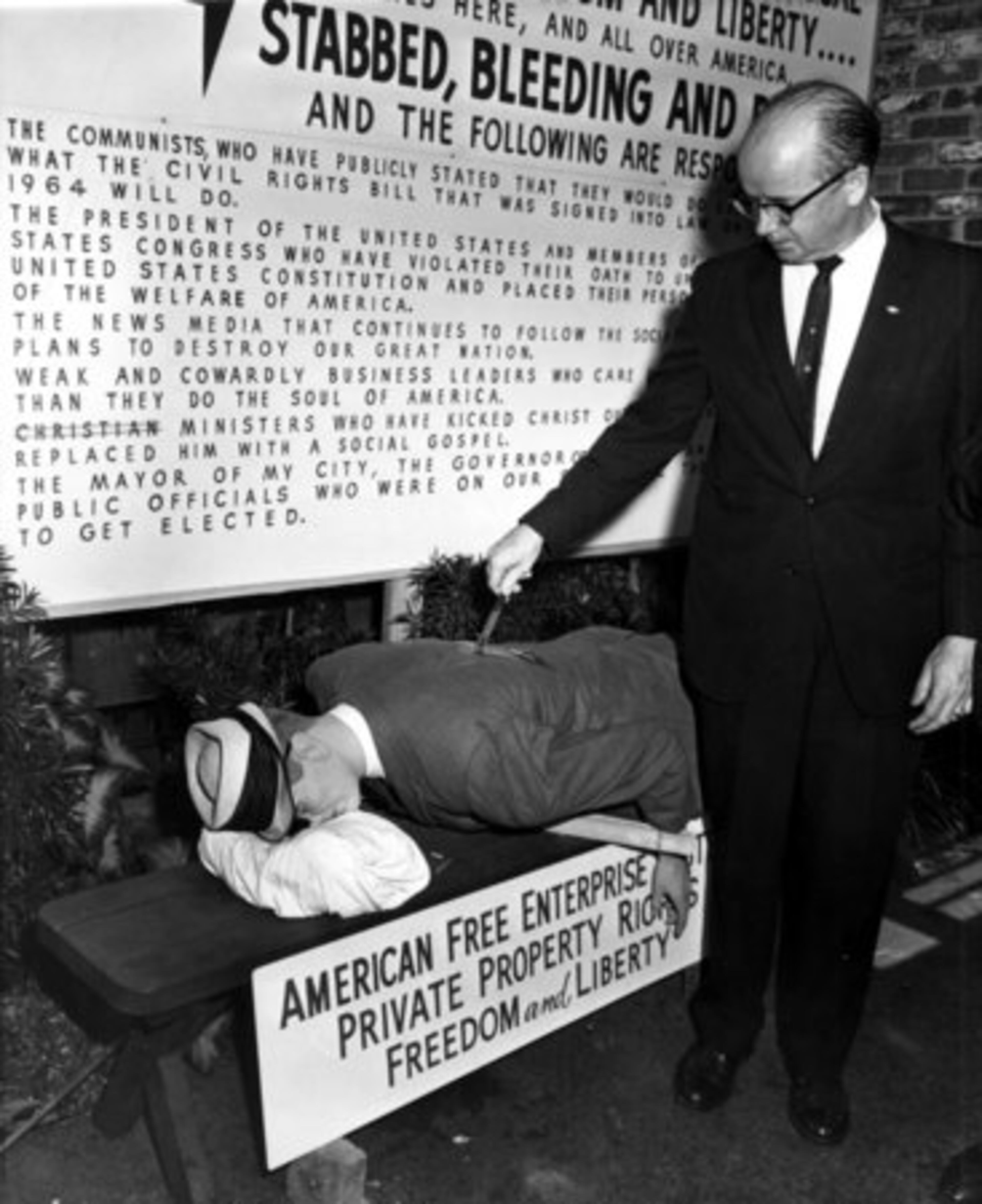 Pickrick Restaurant owner Lester Maddox stabs a mannequin in the back. He said his action represents the death of free enterprise.