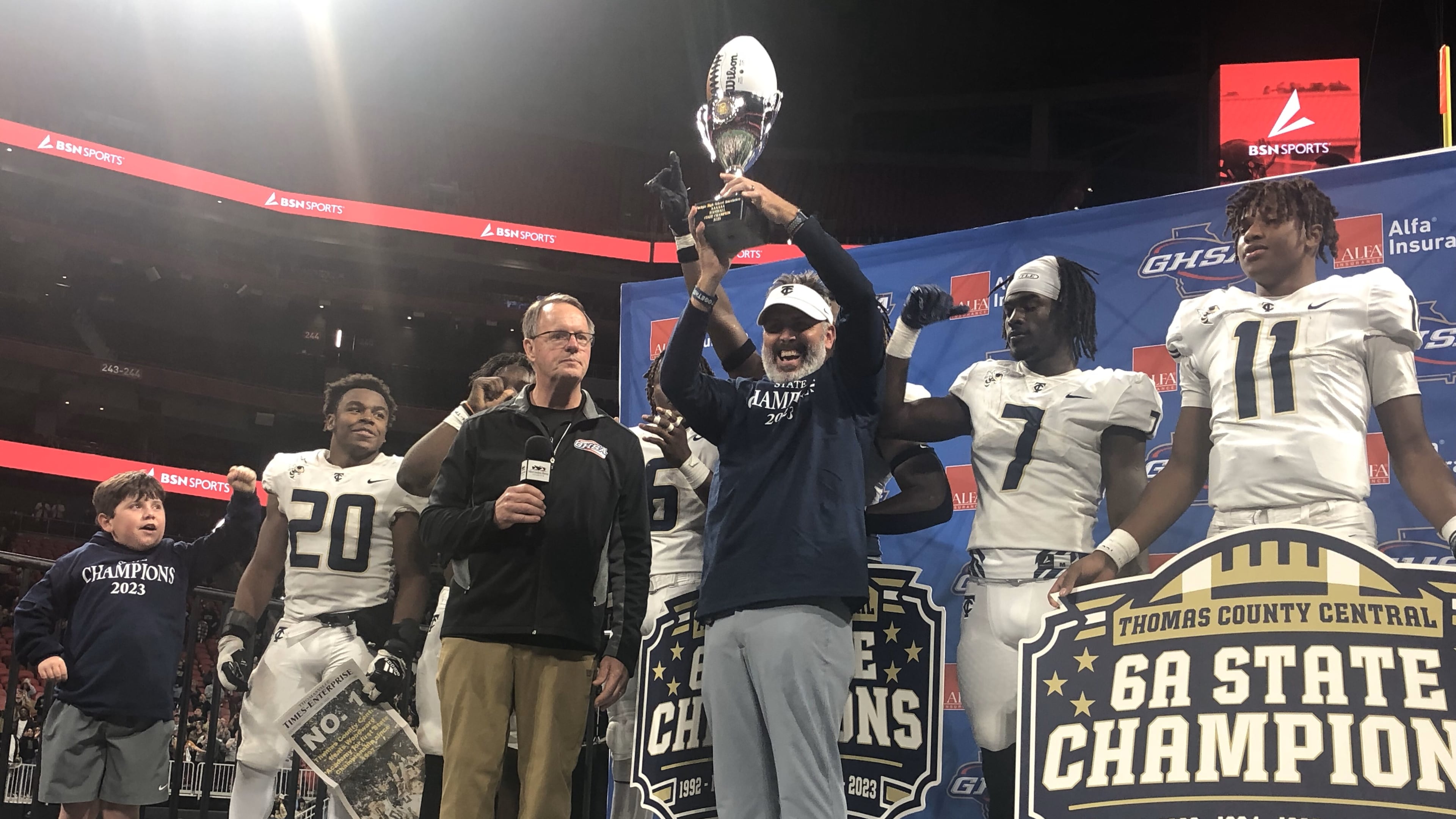 Thomas County Central head coach Justin Rogers accepts the championship trophy from GHSA executive Robin Hines after his teams 49-28 victory over Woodward Academy in the Class 6A final at Mercedes-Benz Stadium on Dec. 12, 2023.