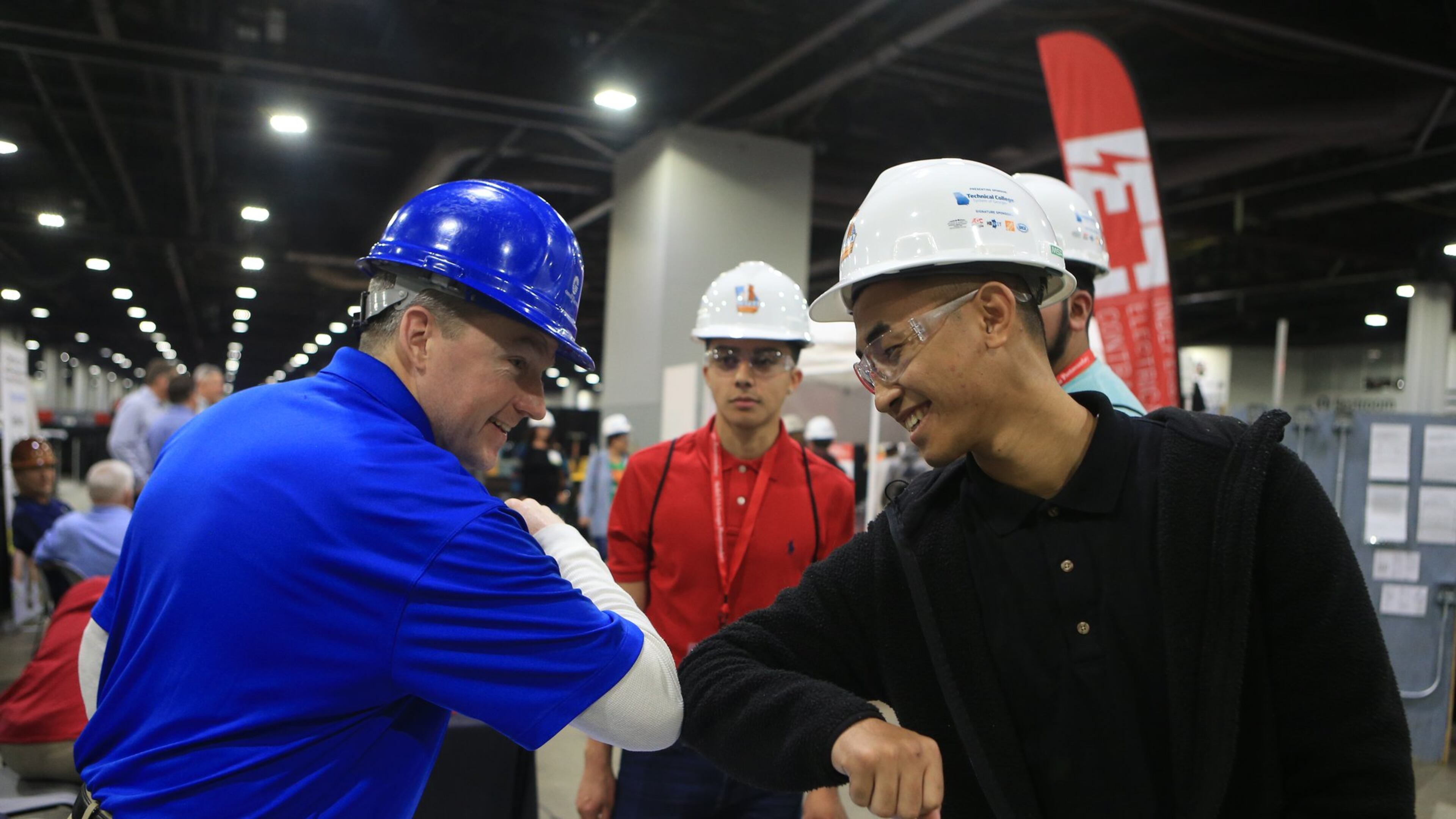 David Shea (left) and Brian Castillo (right) touch elbows during the Construction Education Foundation of Georgia (CEFGA) career expo on Thursday, March 12, 2020, at the Georgia World Congress Center. This year, additional safety measures were implemented, including mandatory hard hats and cleaning wipe-downs. (Christina Matacotta, for The Atlanta Journal-Constitution).