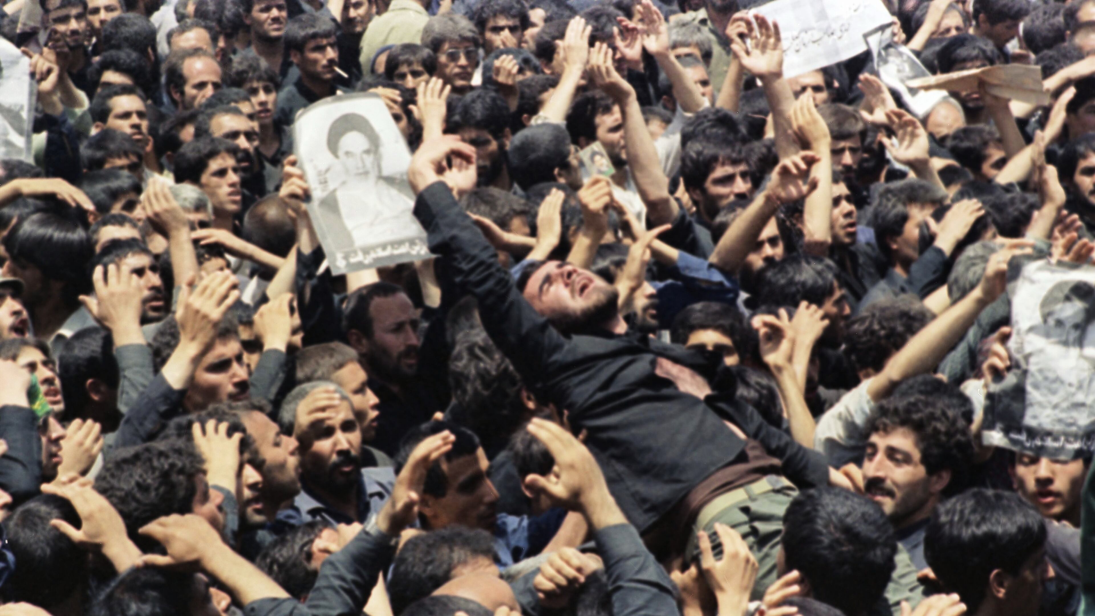 FILE - An Iranian mourner goes into a frenzy just after the body of the Ayatollah Khomeini was removed from Beheshte Zahra Cemetery in Tehran, June 6, 1989. The burial was delayed when thousands of mourners crowded the imam's body in an effort to touch their leader. (AP Photo/Greg English, File)