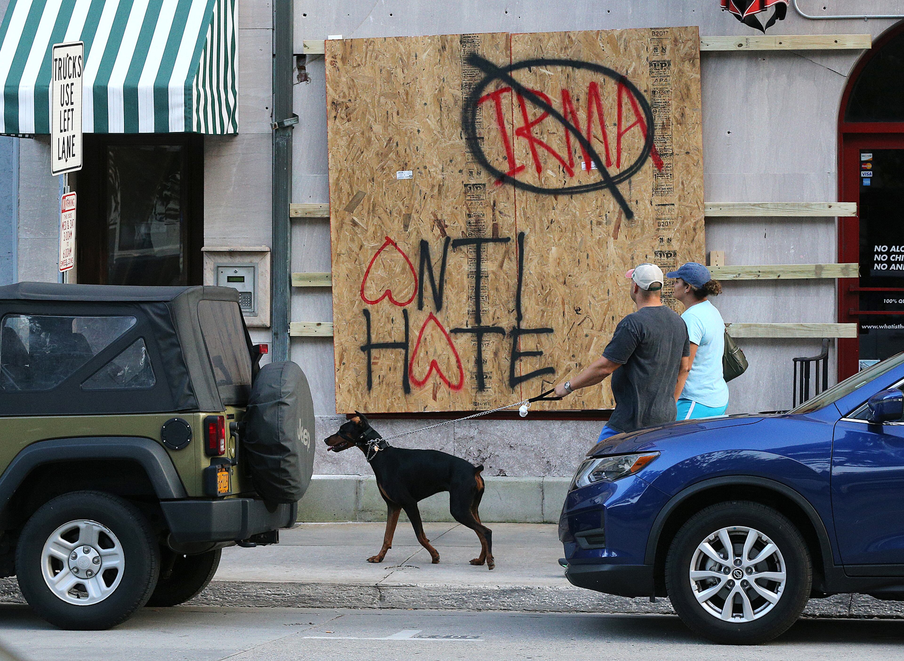 September 8, 2017 Savannah: Eric & Nicole Zajkowski, who just evacuated Hurricane Irma from their home in Coral Springs, Florida, pass by a boarded up store on Bay Street walking their dog Neeko on Friday, September 8, 2017, in Savannah. The city of Savannah is under mandatory evacuation on Saturday and the couple said they will have to evacuate a second time to another location. Curtis Compton/ccompton@ajc.com