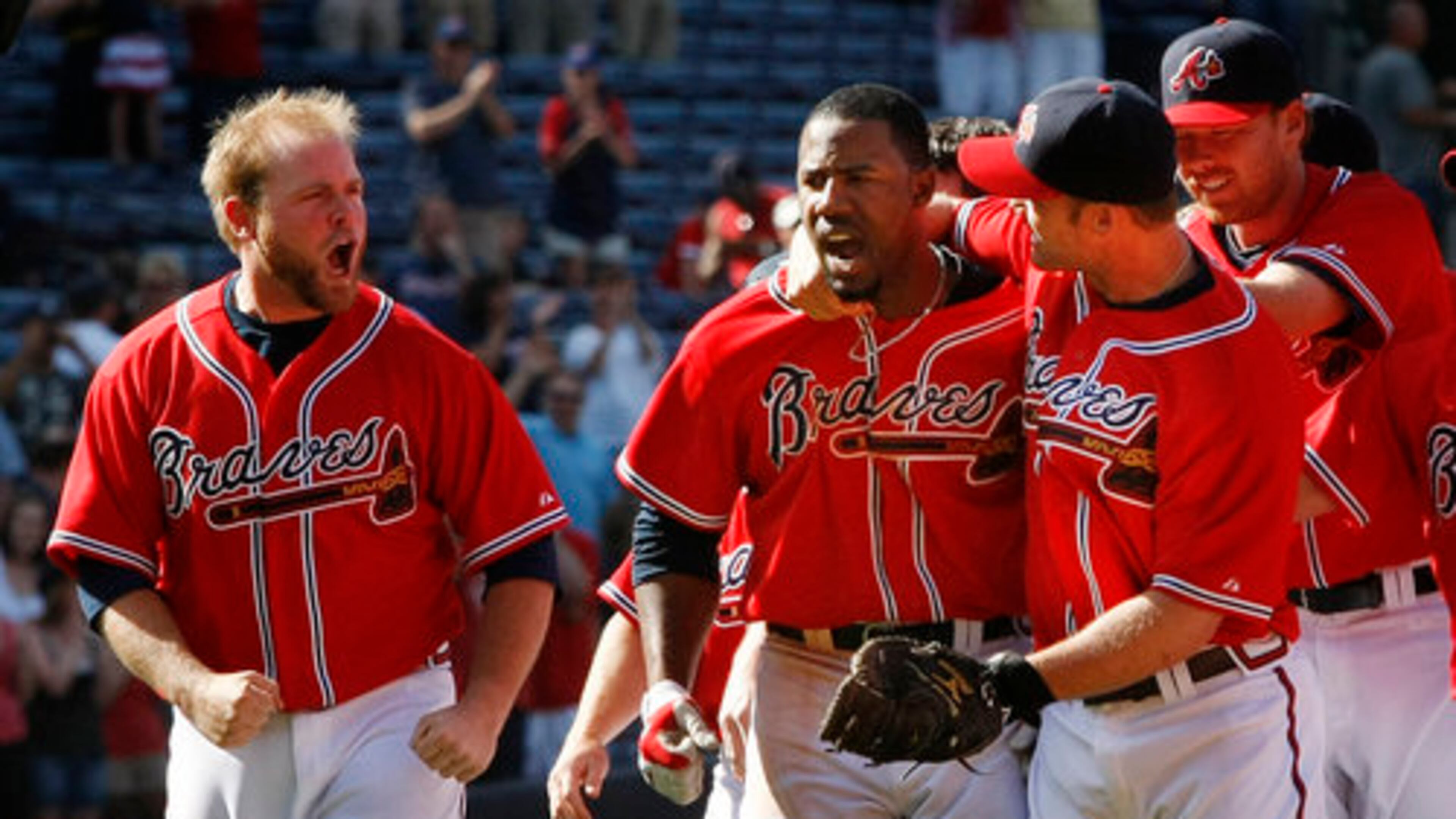 Braves catcher Brian McCann, left, cheers on (22) Jason Heyward, center as he is mobbed by David Ross and the rest of the Braves team after hitting a game winning single to score Martin Prado in the 9th for a 4-3 victory over the Rockies at Turner Field in Atlanta.