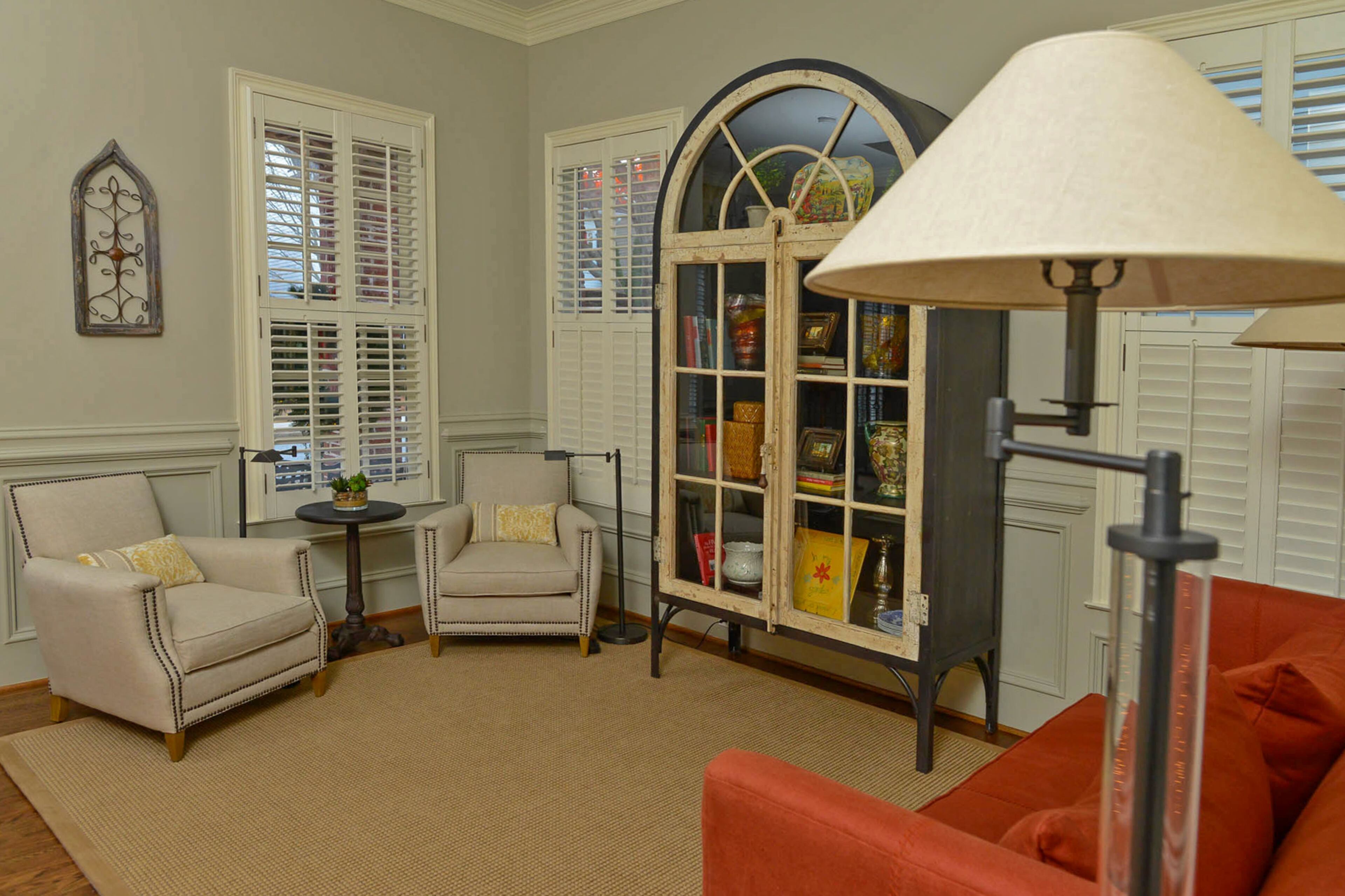 The parlor is decorated with pieces by RH, including the double-door French conservatory cabinet, which is modeled after casement windows but has a contemporary frame made of steel and iron shelves. The arched top mimics the architectural elements on the home's exterior. The walls are painted with Sherwin-Williams Gateway Gray.