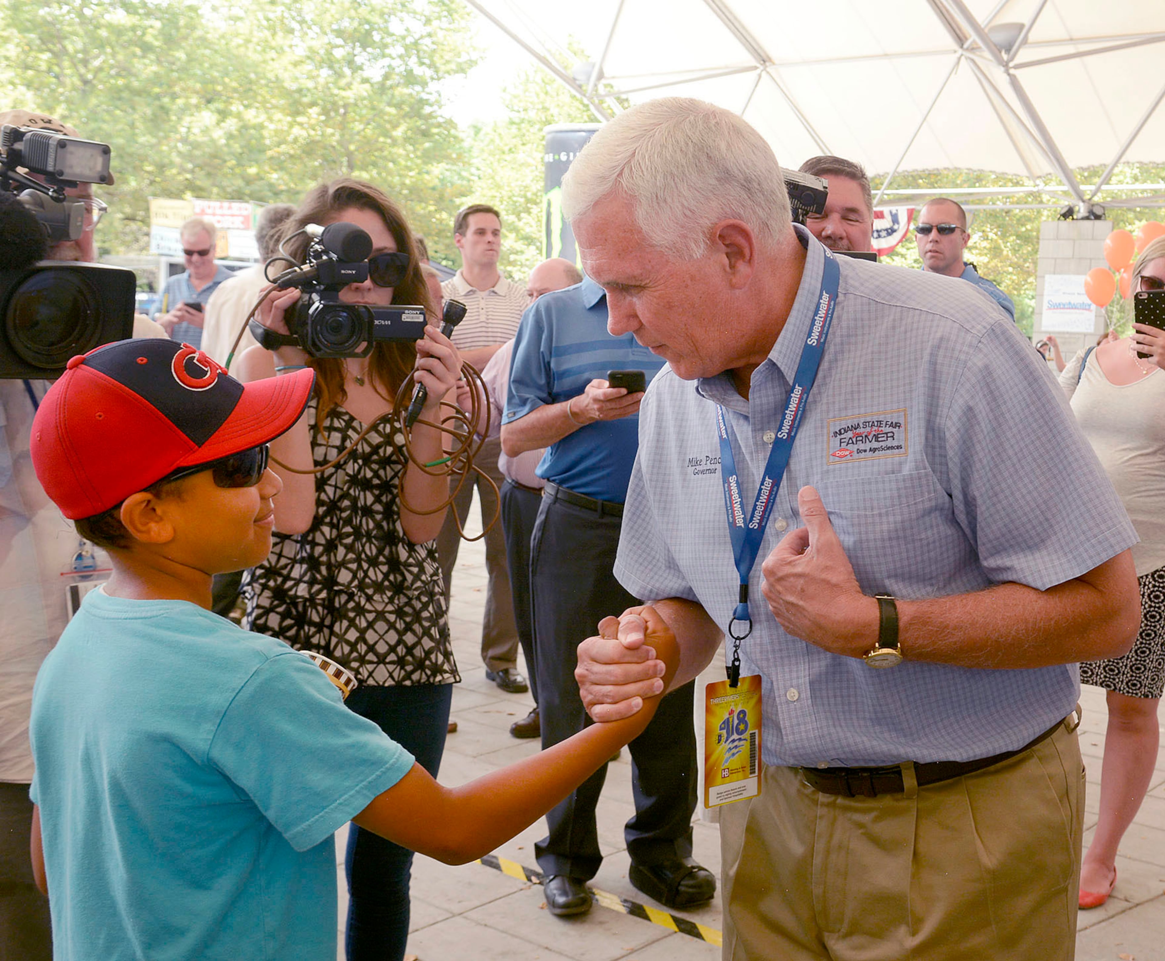 Elijah Morgan, 11, shakes hands with Indiana Governor Mike Pence at the annual Three Rivers Festival in Ft. Wayne, IN, Wednesday, July 13, 2016. The Governor posed for photos, watched a magic trick, drank a lemon shake-up and then answered questions about his meetings with Donald Trump. Pence repeated his earlier statement that nothing was offered by Trump and nothing was accepted by him. (Samuel Hoffman/The Journal-Gazette via AP)