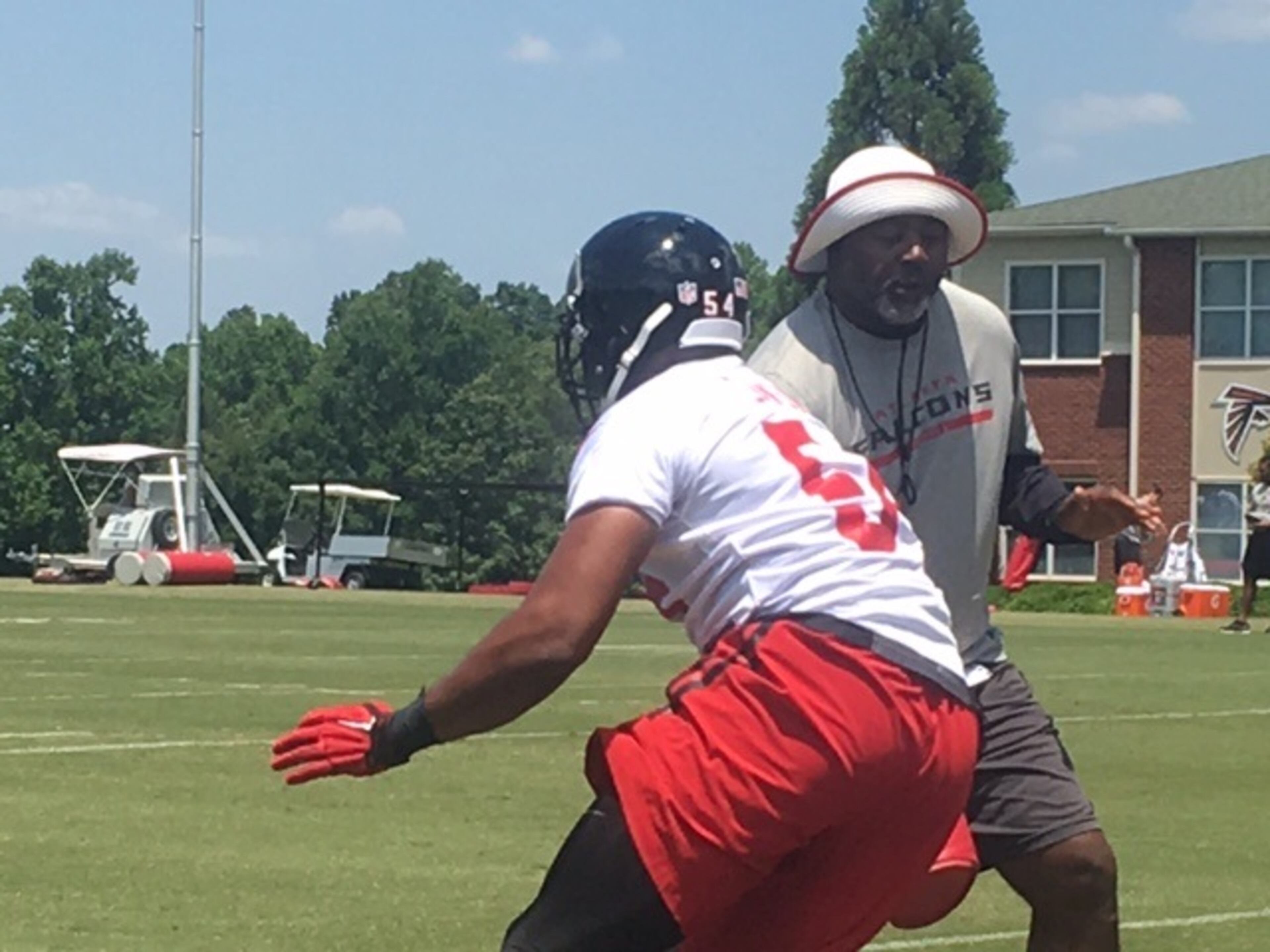 Falcons defensive line coach Bryan Cox working with a player in a pass rush agility drill on Monday. (By D. Orlando Ledbetter/dledbetter@ajc.com)