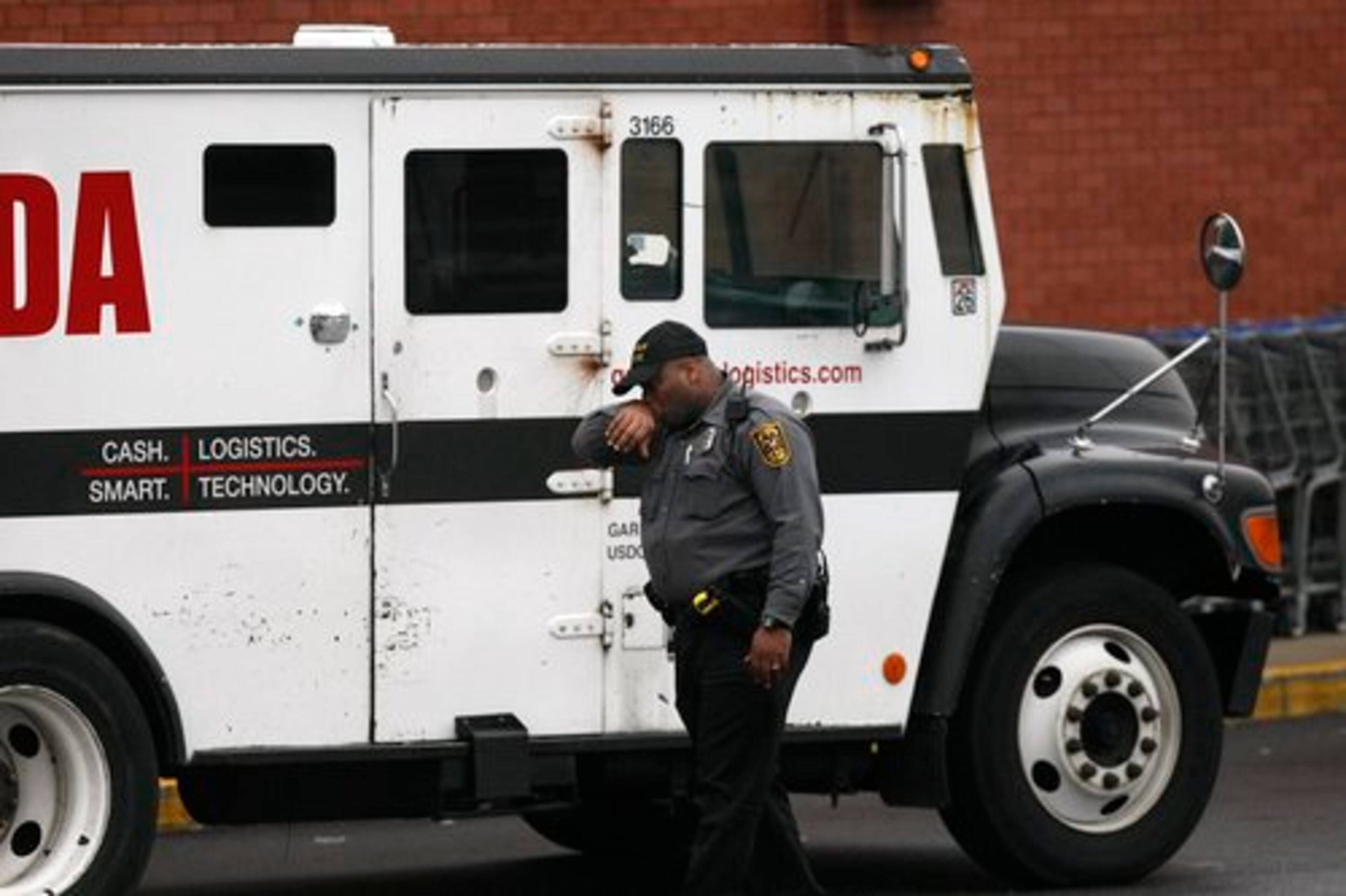 A DeKalb County police officer looks over the scene where two men killed a guard in a daring armored car robbery at the Kroger on Lavista Road at North Druid Hills in Atlanta on Tuesday, March 15, 2011. The guard, who was shot three times after leaving the Toco Hill Kroger with cash at noon Tuesday, died later in the day at the hospital.