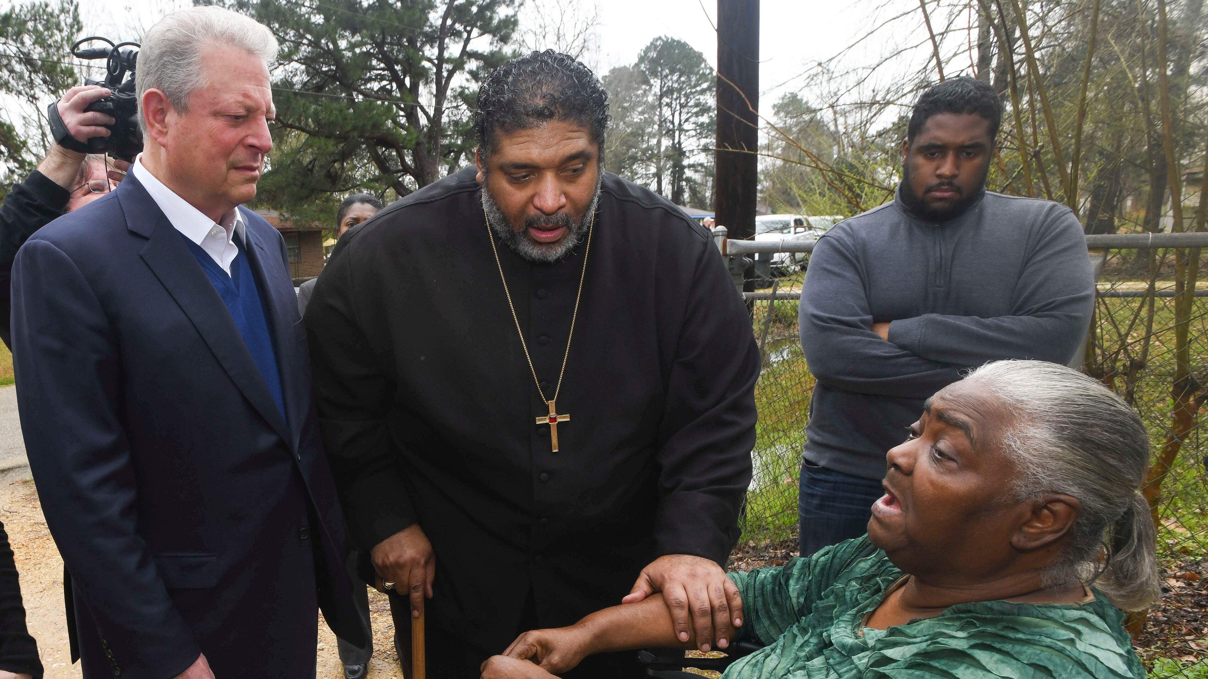 FILE - In this Feb. 21, 2019, file photo, former Vice President Al Gore, left, founder of the Climate Reality Project, and the Rev. William Barber II, president of the Repairers of the Breach, visit Lowndes County resident Charlie Mae Holcombe to talk about the failing wastewater sanitation system at her home in Hayneville, Ala. An anti-poverty coalition led by Barber is scheduled to hold a virtual march Saturday. The Mass Poor People’s Assembly & Moral March on Washington aims to build upon the nation’s principles to pursue solutions to poverty — something advocates say is getting especially severe in rural areas. (AP Photo/Julie Bennett, File)