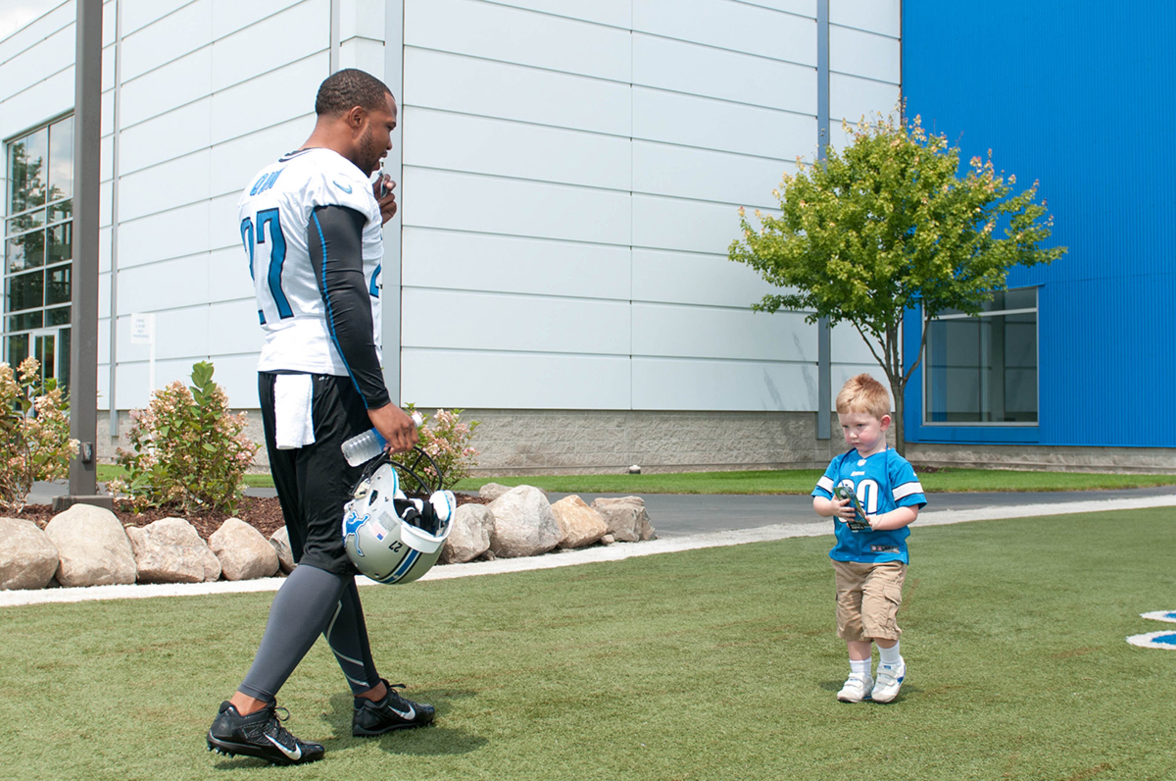 Detroit Lions safety Glover Quin (27) talks to a young fan before training camp at the Detroit Lions training facility in Allen Park, Mich.