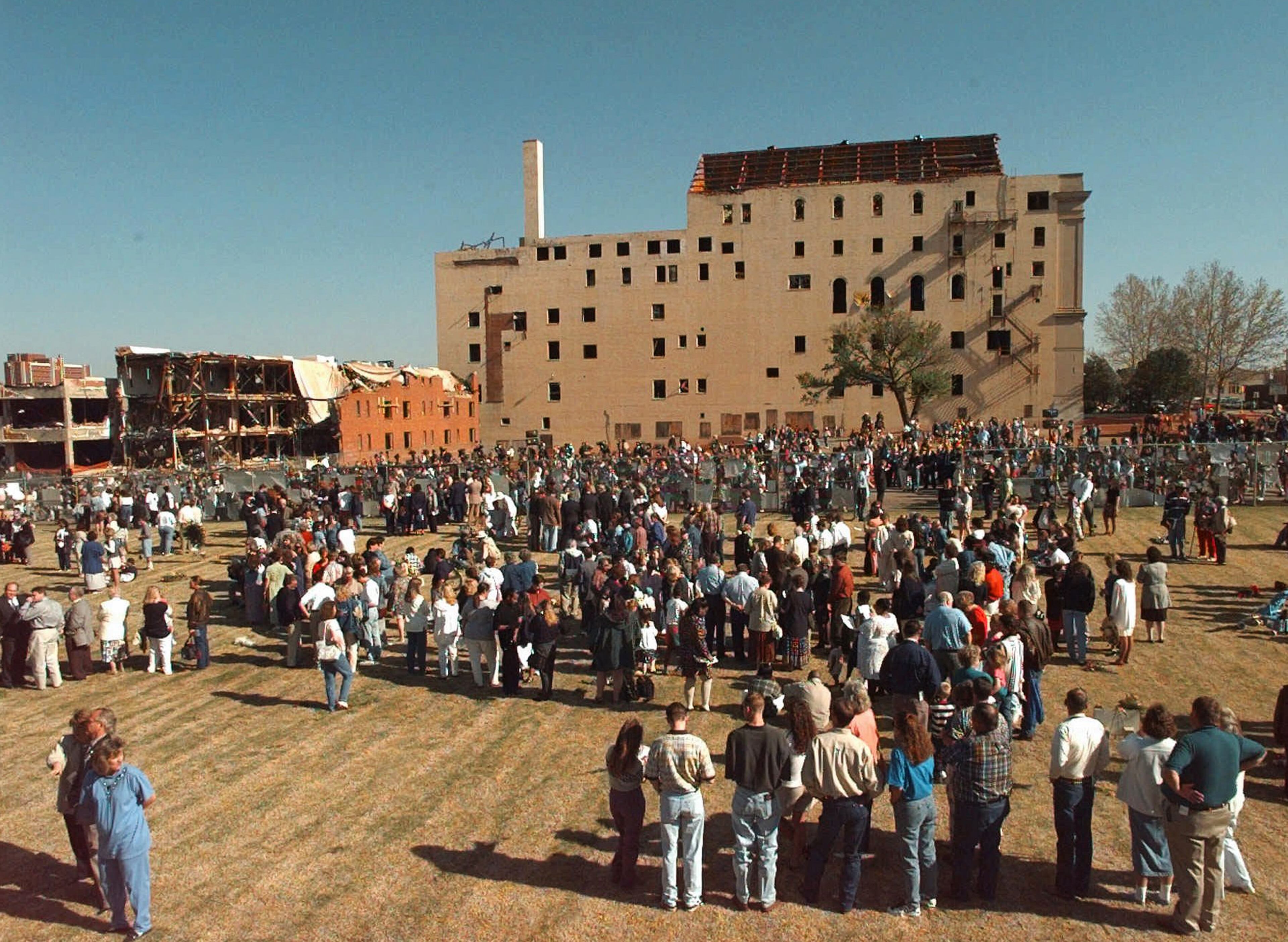 In this April 19, 1997 file photo, family members of those who died in the Oklahoma City bombing two years ago, stand on the ground where the Alfred P. Murrah Federal Building once stood, during the second anniversary memorial ceremony. A memorial to the bombing victims now sits on the former site of the federal building, and a nearby building that was damaged in the bombing houses an interactive museum. Each year on the bombing anniversary, victim's family members, survivors, rescue workers and others return to the memorial for a remembrance ceremony.(AP Photo/J. Pat Carter, POOL)