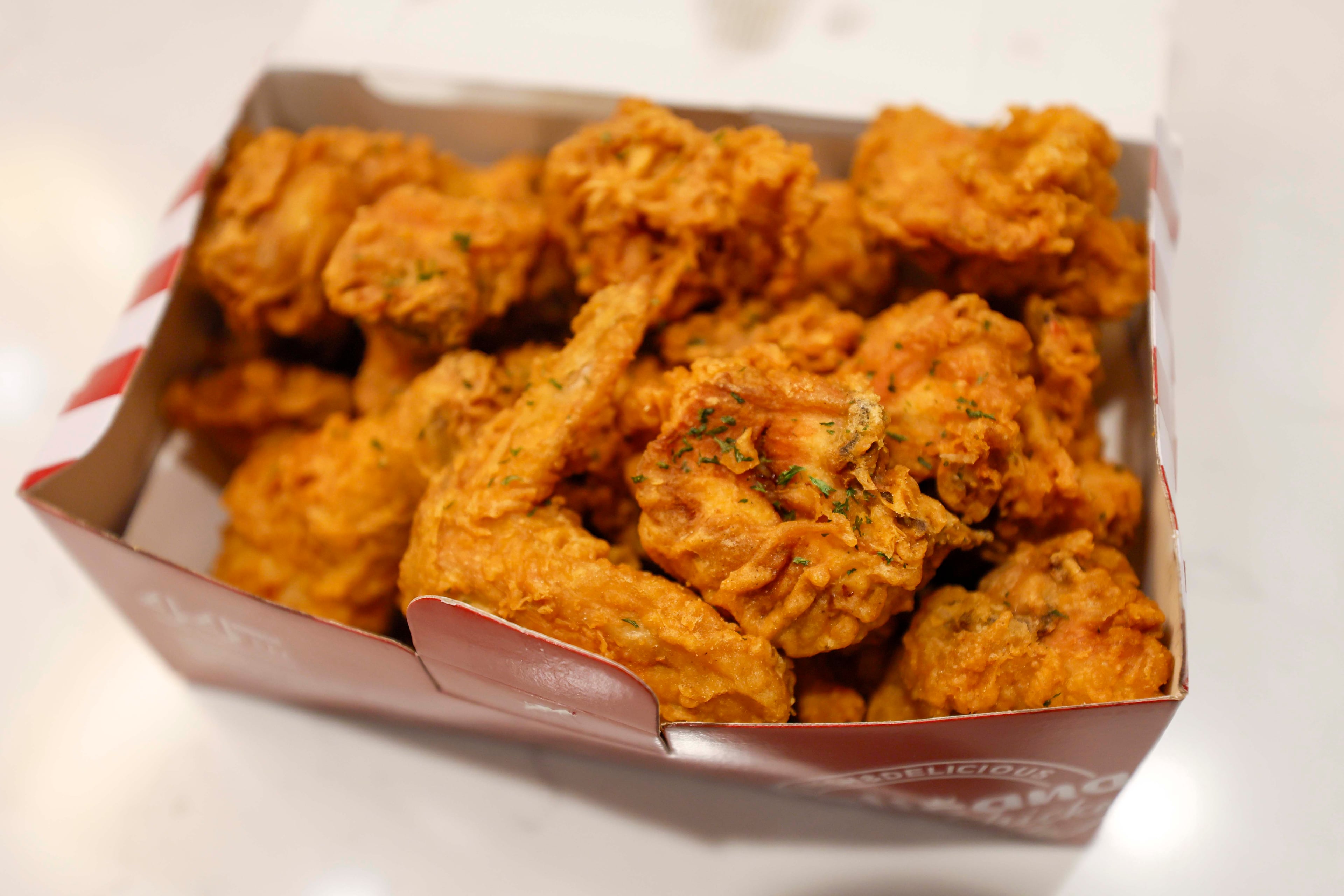 A box filled with pieces of Pelicana chicken is displayed at the Atlanta Journal-Constitution office, where the food expert and guest will be participating in a contest on Tuesday, Aug. 25, 2026, to determine the best fried chicken in Atlanta. (Miguel Martinez/AJC)