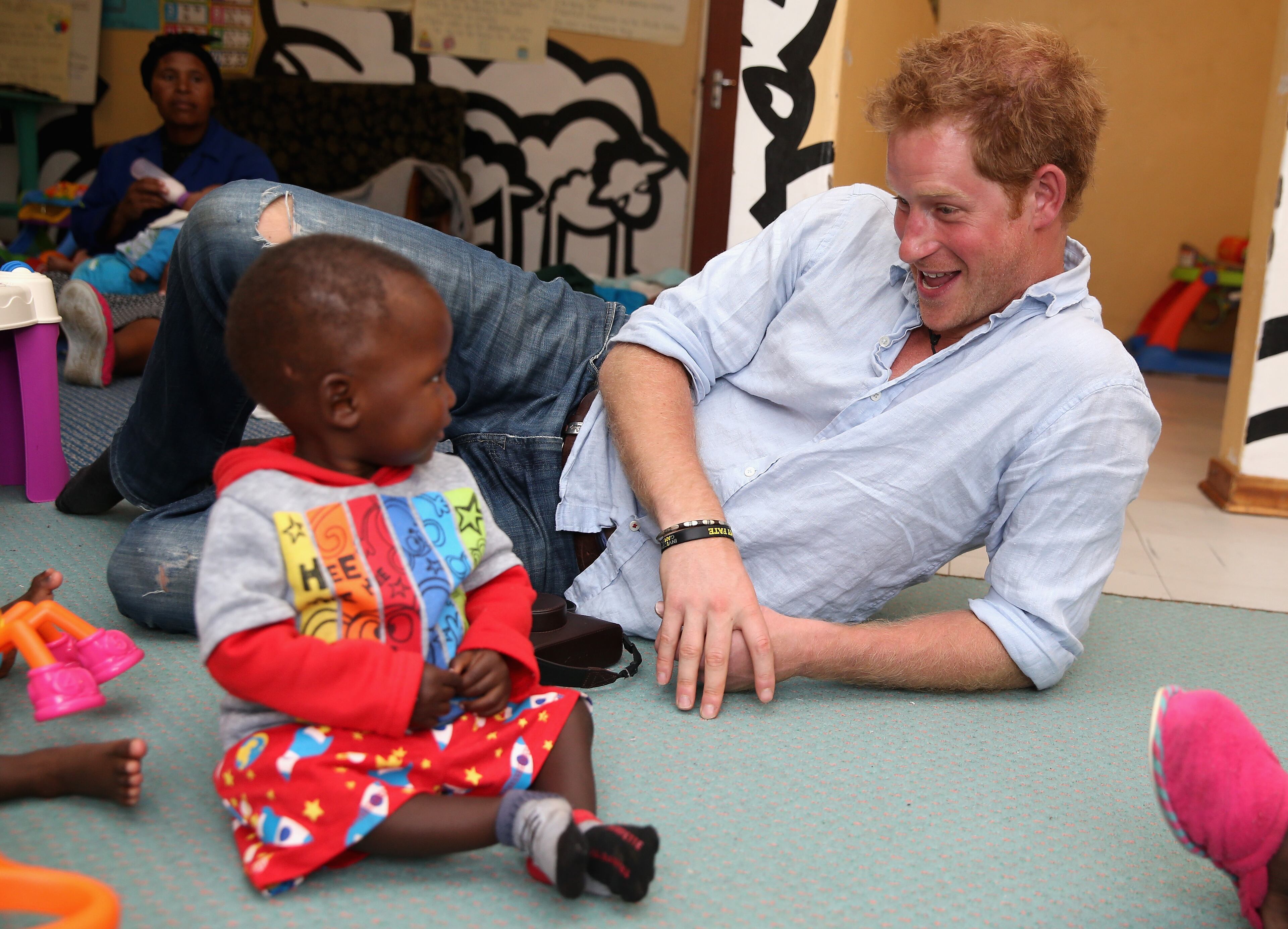 Prince Harry plays with two young children (who are going through a programme for malnourishment) during a visit to the organisation supported by Sentebale 'Touching Tiny Lives' on December 8, 2014 in Mokhotlong, Lesotho. Prince Harry was visiting Lesotho to see the work of his charity Sentebale. Sentebale provides healthcare and education to vulnerable children in Lesotho, Southern Africa. The particular theme of his visit was to check on the progress of the Mamohato Childrens Centre which will provide vital support to children affected by HIV. Prince Harry founded Sentebale (which means Forget Me Not in Sesotho) with Prince Seeiso in 2006. (Photo by Chris Jackson/Getty Images for Sentebale)