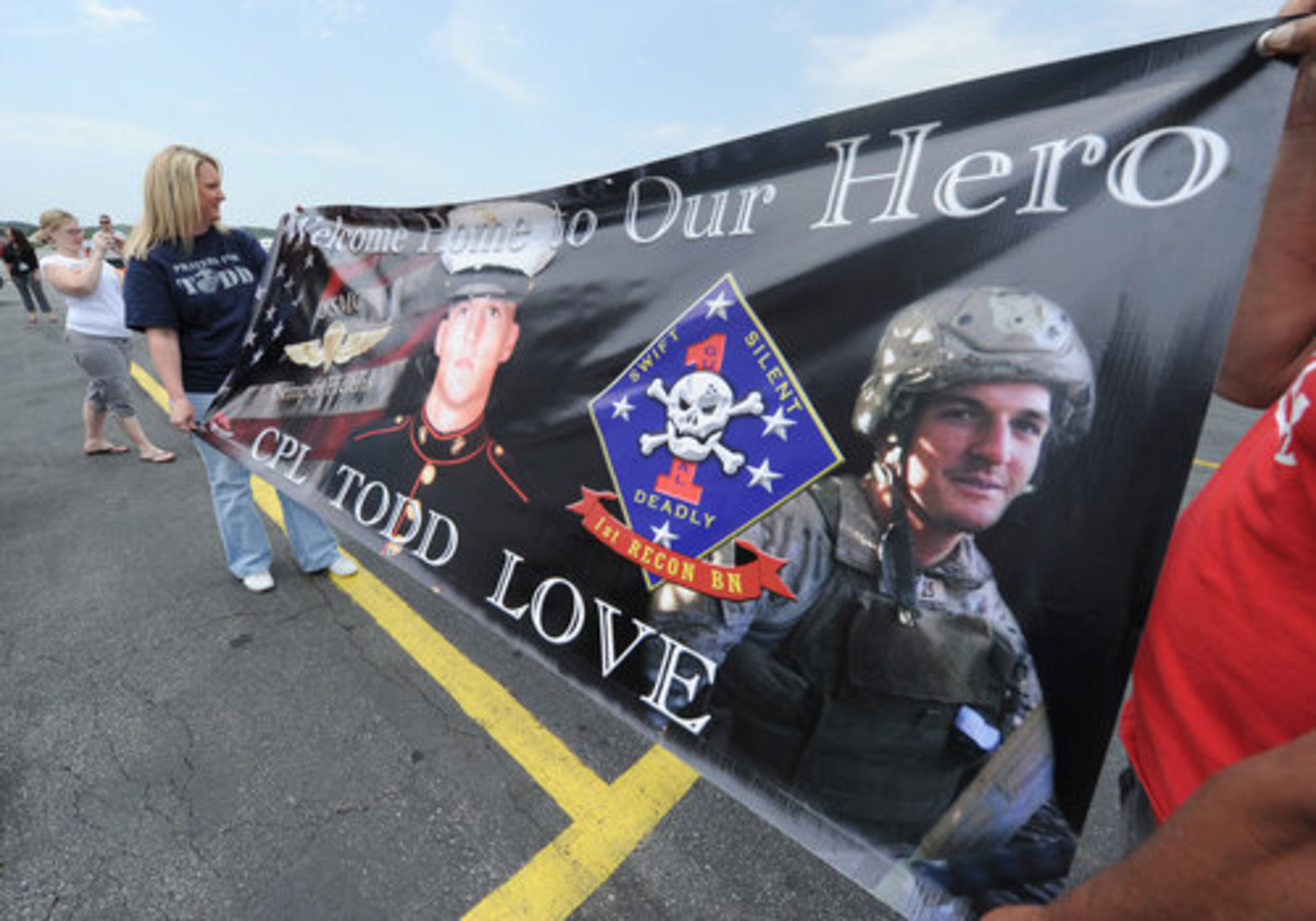 Mindi Bennett holds a sign welcoming home Marine Cpl. Todd Simpson Love at McCollum Field.