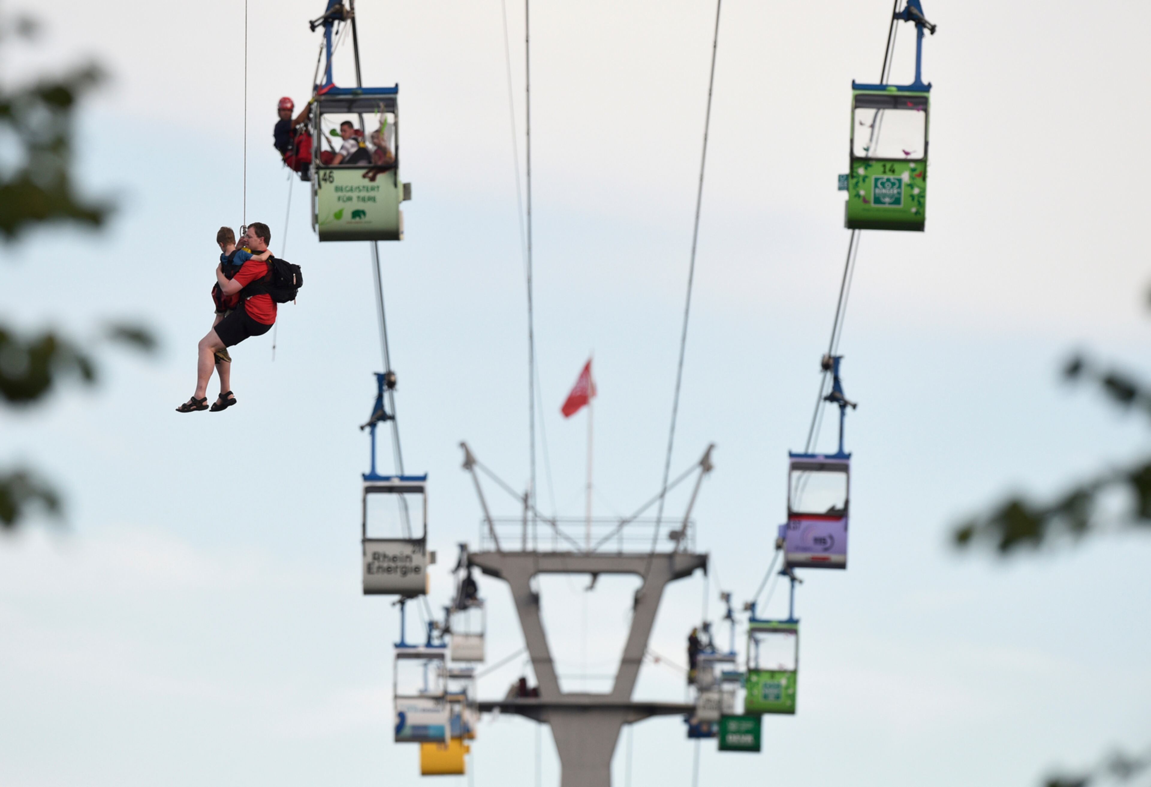 Members of the fire service rescue people from cable car gondolas, in Cologne, Germany, Sunday, July 30, 2017. A gondola of a cable car across the river Rhine became stuck on Sunday. (Rainer Jensen/dpa via AP)
