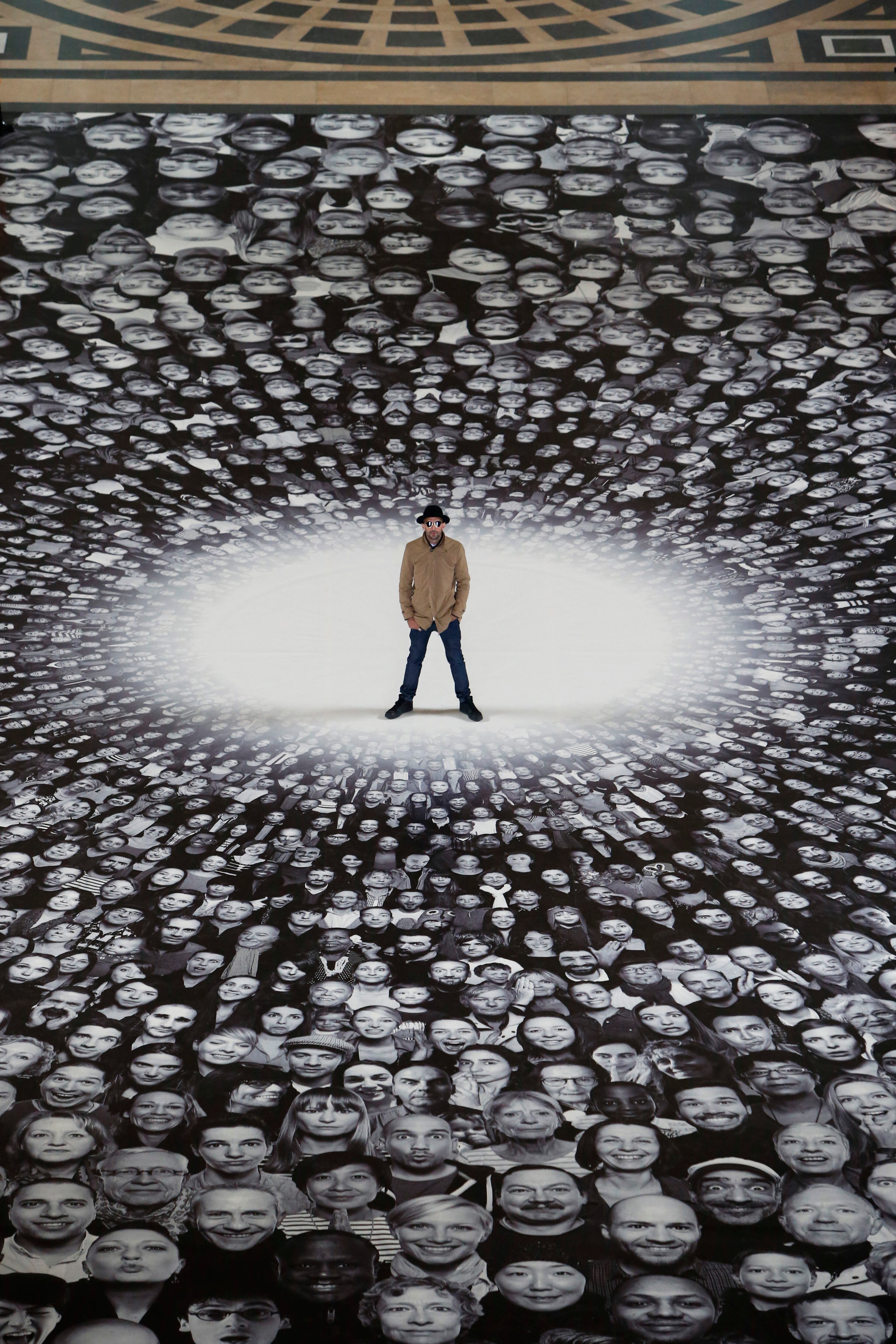 French street artist and photographer JR poses on his creation during the presentation to the press at the Pantheon in Paris, Tuesday, June 3, 2014. French Government named JR to decorate with portraits of Paris' Pantheon, that is the final resting place for 72 of France's renowned men, and just one woman, as the monument is undergoing a 2 year renovation. (AP Photo/Francois Mori)