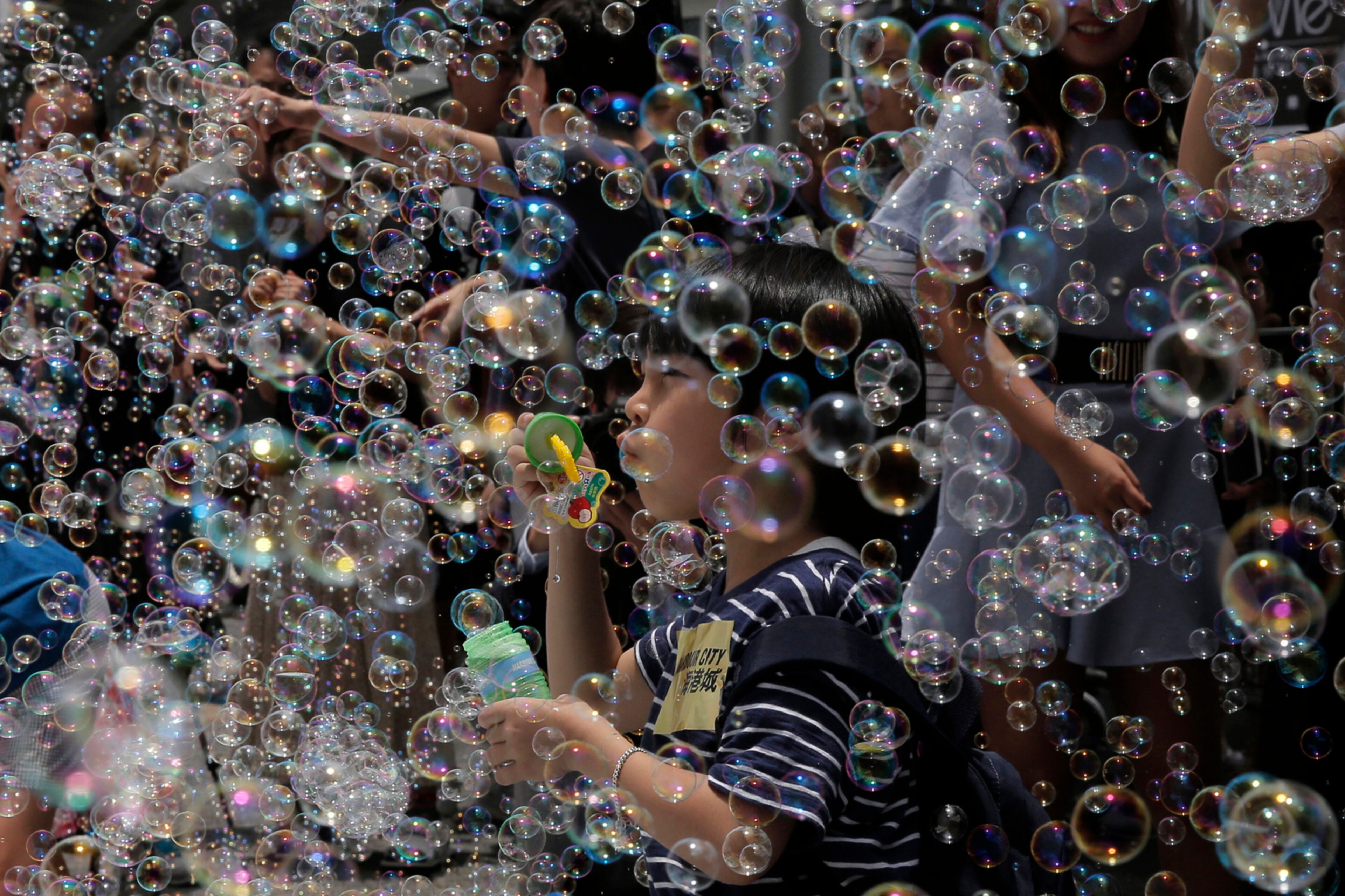 A boy plays with bubbles during an art display titled "Bubble Up" created by Japanese artist Shinji Ohmaki in Hong Kong, Wednesday, Aug. 2, 2017. (AP Photo/Kin Cheung)