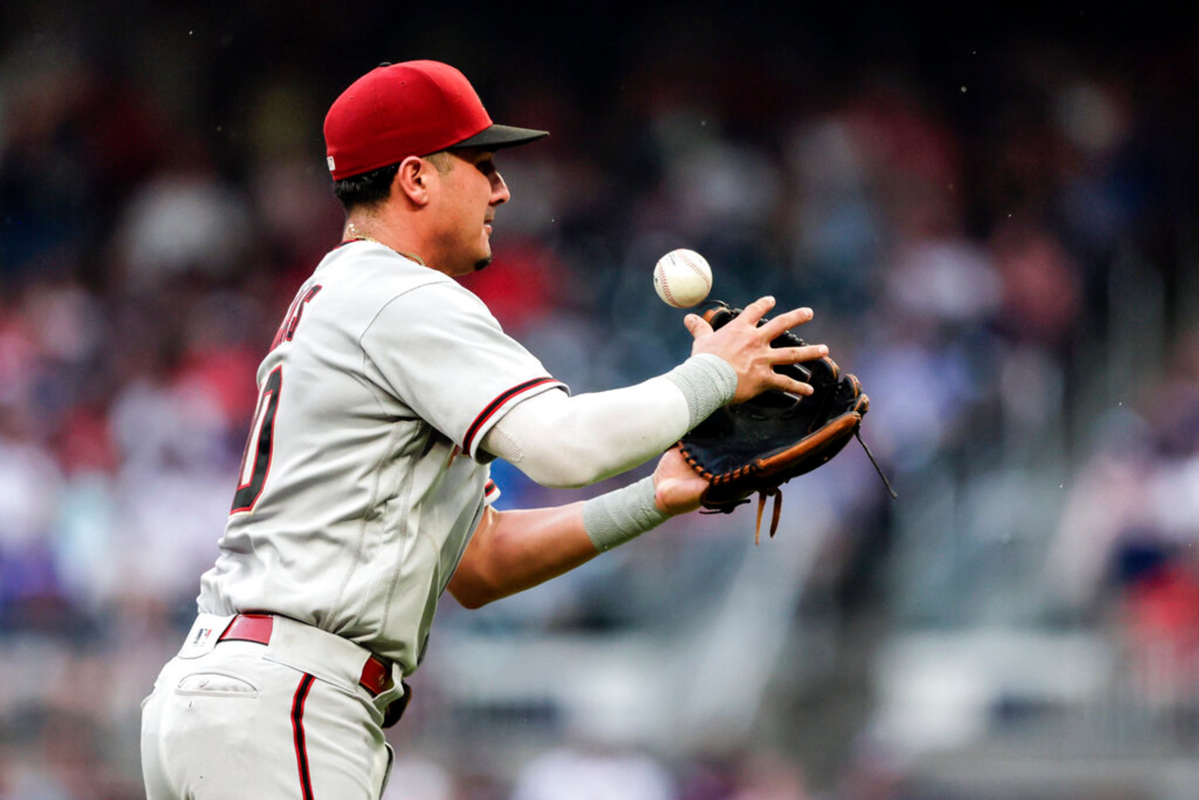 Arizona Diamondbacks third baseman Josh Rojas bobbles a ball hit by Atlanta Braves' Ronald Acuña Jr., who reached on the error during the second inning of a baseball game Saturday, July 30, 2022, in Atlanta. (AP Photo/Butch Dill)