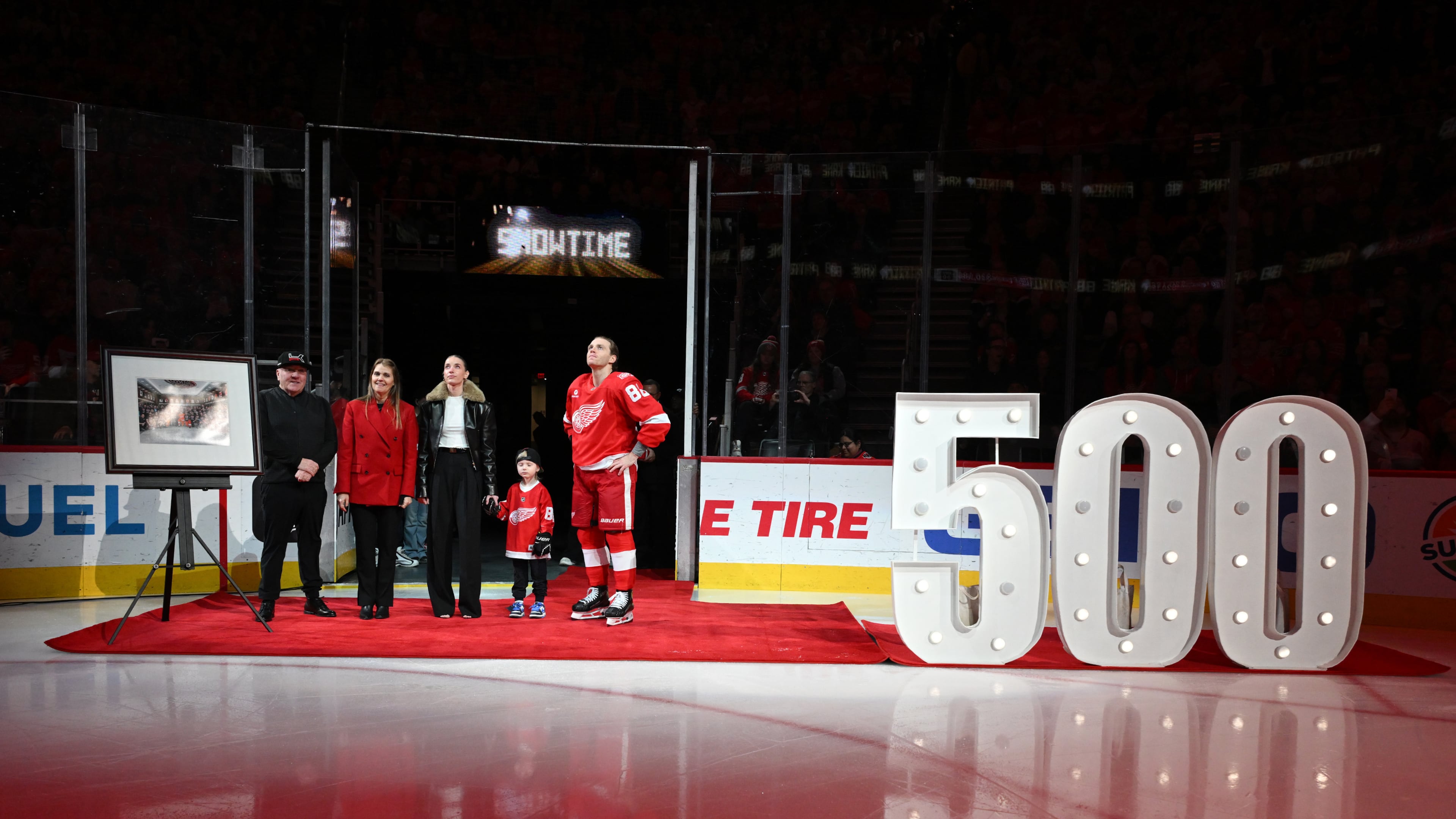 Detroit Red Wings right wing Patrick Kane (88) stands with his family, from left to right, father Patrick Sr., mother Donna, girlfriend Amanda Grahovec, and son Patrick III while being honored by the team for scoring his 500th career goal earlier in the month before an NHL hockey game against the Ottawa Senators, Sunday, Jan. 18, 2026, in Detroit. (AP Photo/Lon Horwedel)