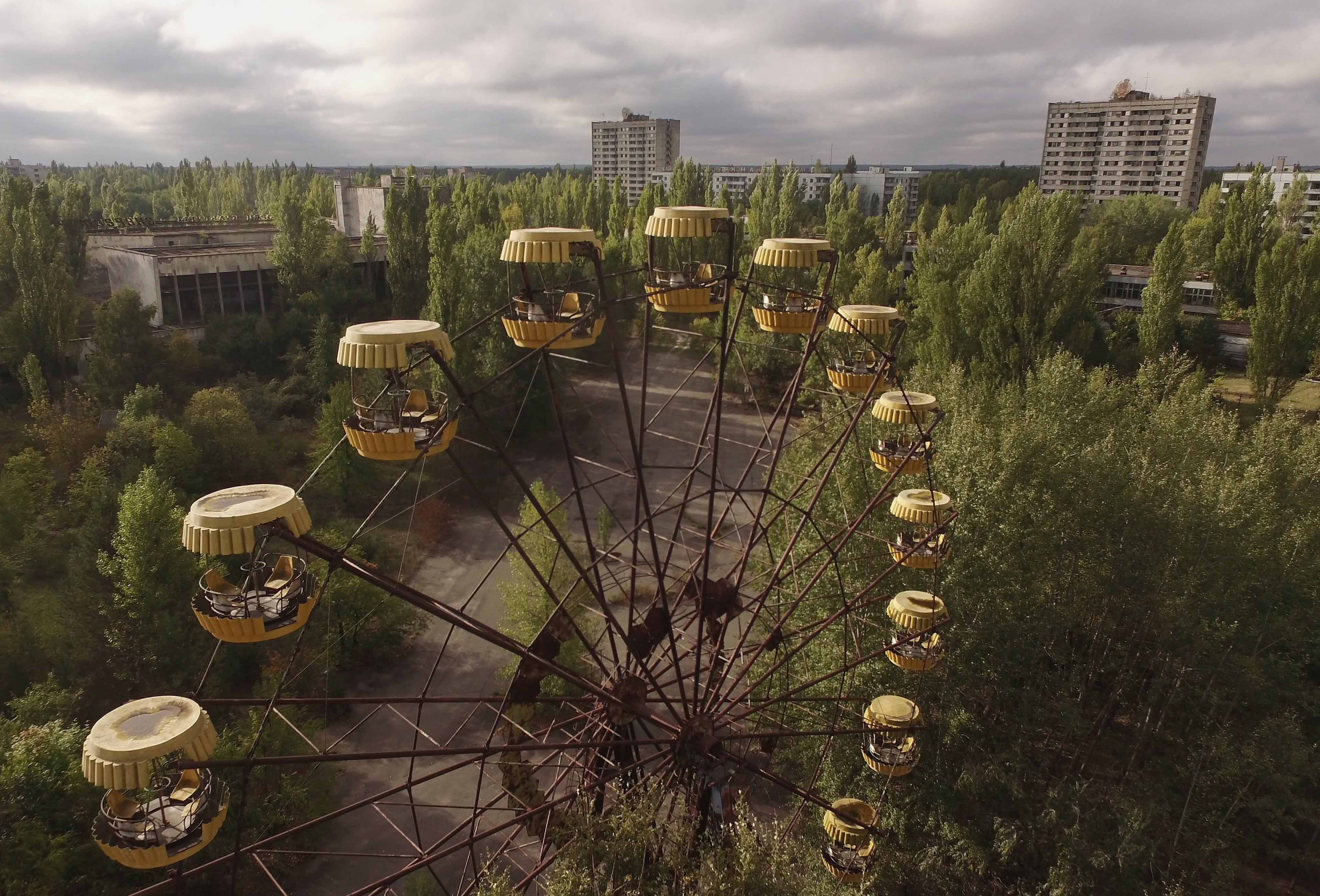 PRIPYAT, UKRAINE - SEPTEMBER 30: In this aerial view an abandoned ferris wheel stands on a public space overgrown with trees in the former city center on September 30, 2015 in Pripyat, Ukraine. Pripyat lies only a few kilometers from the former Chernobyl nuclear power plant and was built in the 1970s to house the plant's workers and their families. On April 26, 1986, technicians at Chernobyl conducting a test inadvertently caused reactor number four to explode, sending plumes of highly radioactive particles and debris into the atmosphere. Authorities evacuated 120,000 people from the area, including 43,000 from Pripyat. Today Pripyat is a ghost-town, its apartment buildings, shops, restaurants, hospital, schools, cultural center and sports facilities derelict and its streets overgrown with trees. The city lies in the inner exclusion zone around Chernobyl where hot spots of persistently high levels of radiation make the area uninhabitable for thousands of years to come. (Photo by Sean Gallup/Getty Images)