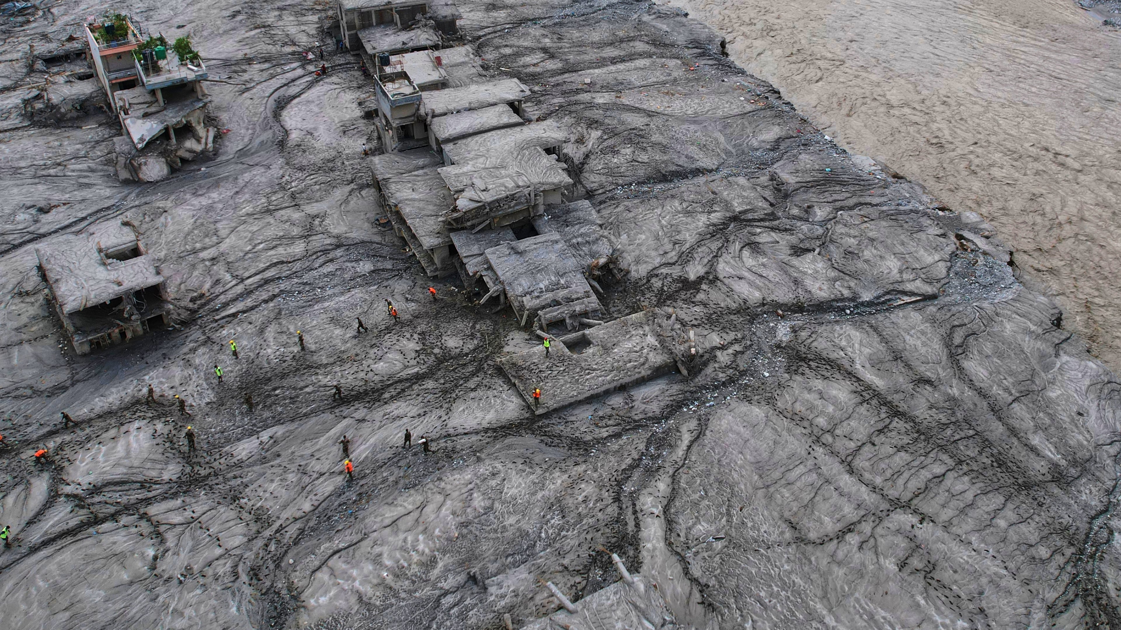 A drone view shows rescue workers inspect the area and damaged structures following recent flash flooding along the Trishuli River in the Devighat area of Nuwakot district, Nepal, Saturday, Aug. 29, 2026. (AP Photo/Rajesh Kumar Singh)