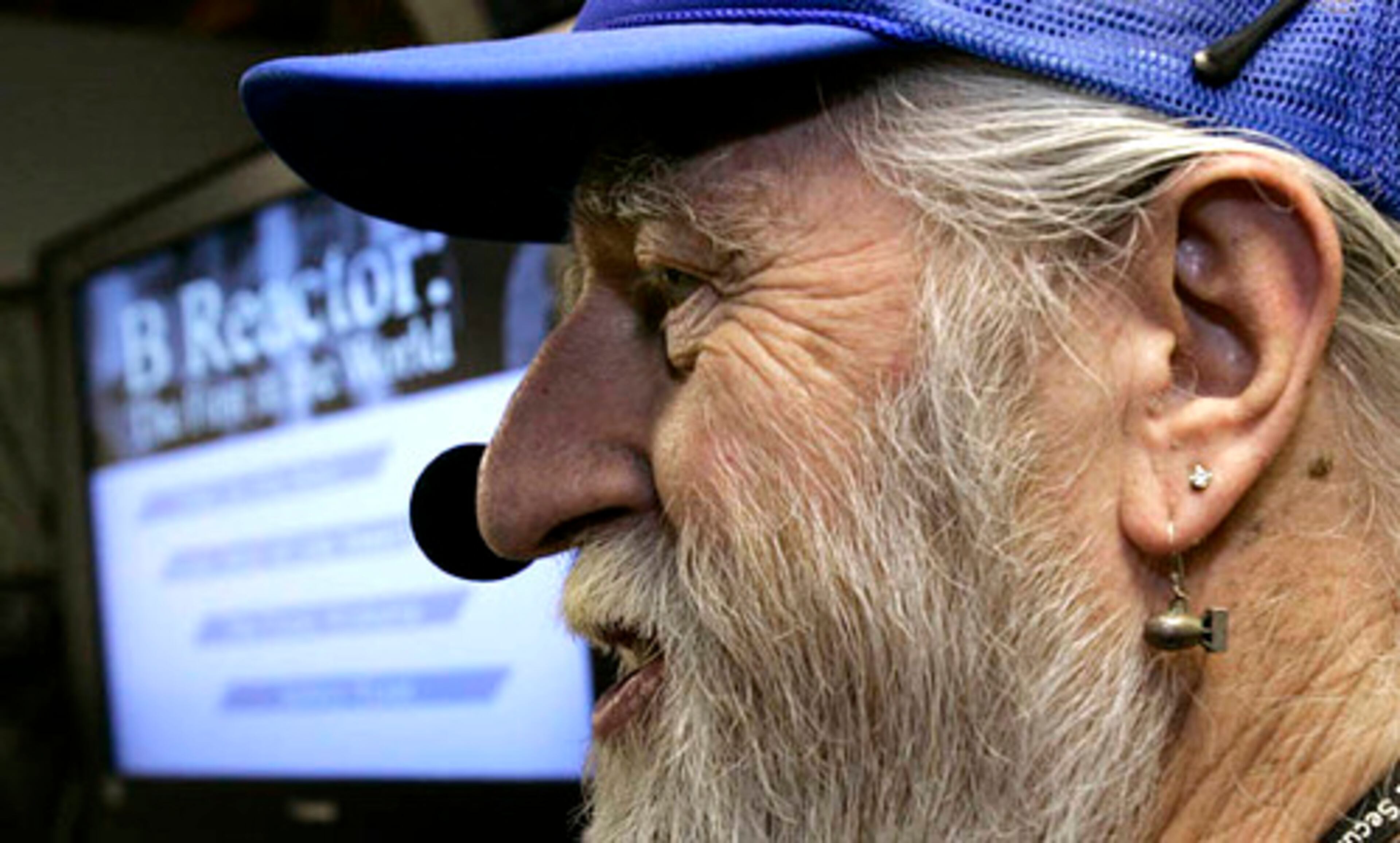 Burt Pierard wears an earing in the shape of a nuclear bomb as he talks to visitors on a public tour of the Hanford nuclear reservation.