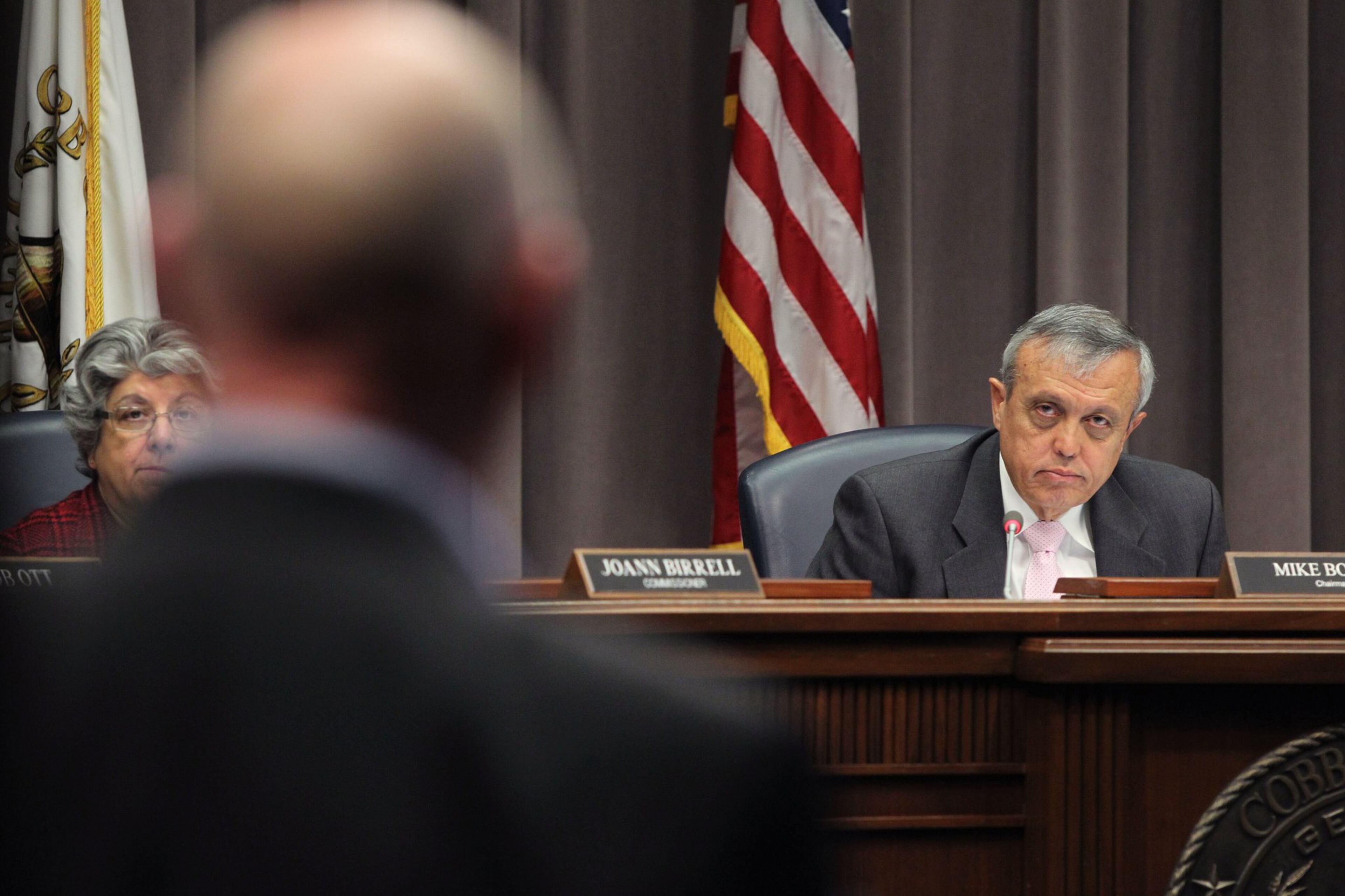 Mike Boyce, chairman of the Cobb County Commission, listens to a speaker in Marietta.