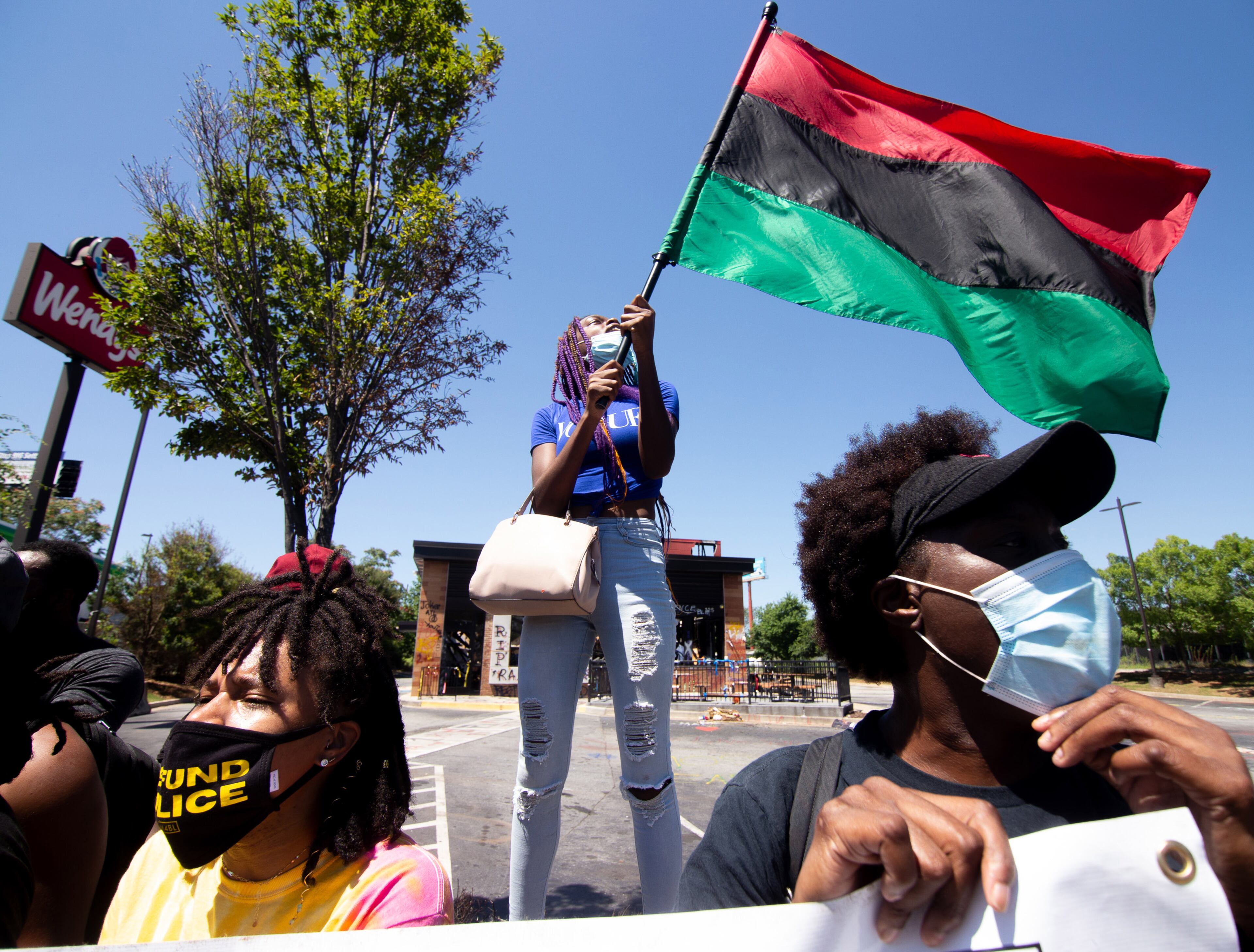 Yvette Dixon waves her flag during a rally at the Wendy's on University Avenue in Atlanta on Saturday, July 11, 2020. STEVE SCHAEFER FOR THE ATLANTA JOURNAL-CONSTITUTION