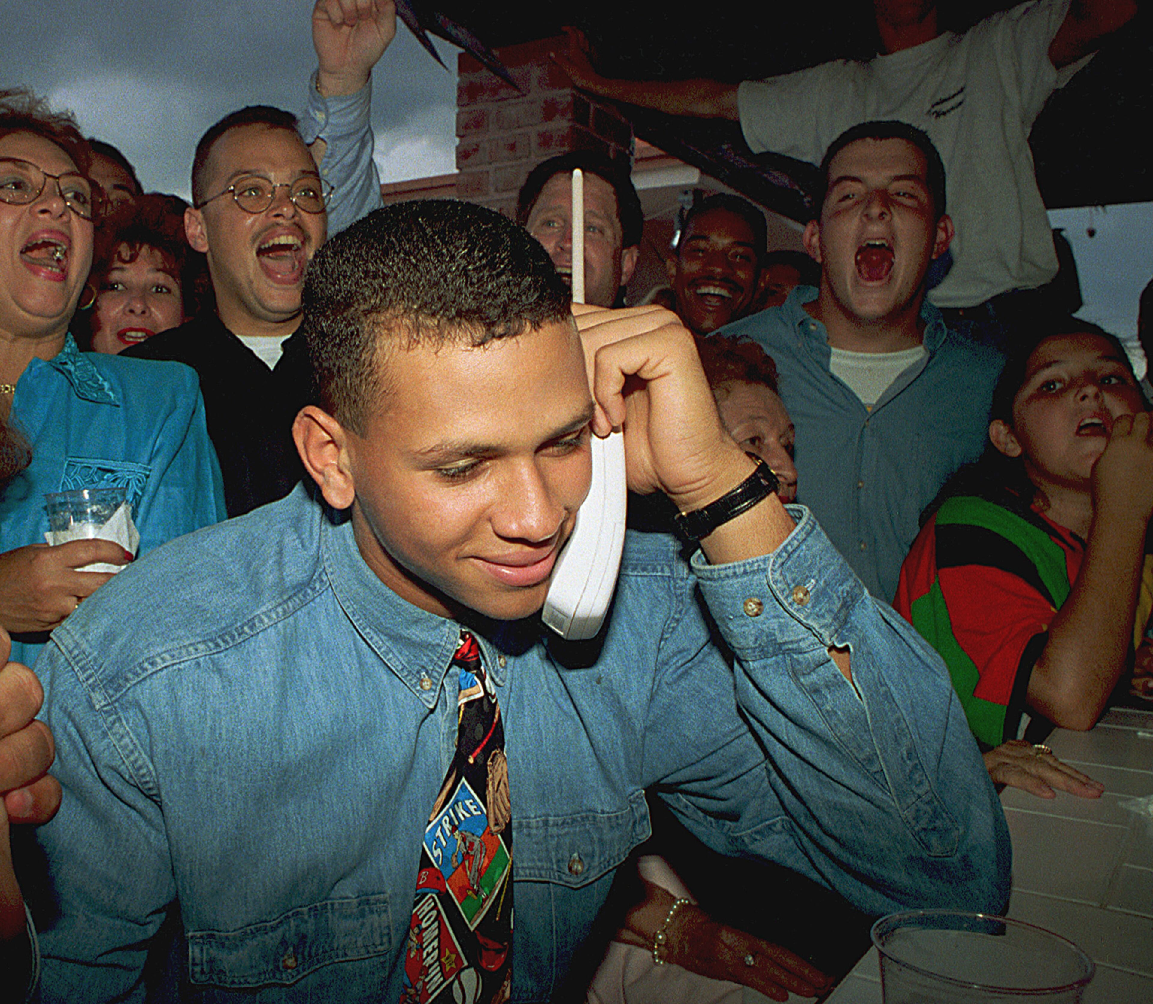 1993: Alex Rodriguez listens on the telephone as the Seattle Mariners ask him to join their team as the No. 1 pick in the baseball draft amid cheers from his mother, Lourdes, left, and friends in Miami. Three MVP awards, 14 All-Star selections, two record-setting contracts and countless controversies later, A-Rod is the biggest and wealthiest target of an investigation into performance-enhancing drugs, with a decision from baseball Commissioner Bud Selig expected on Monday, Aug. 5, 2013. (AP Photo/Marta Lavandier, File)