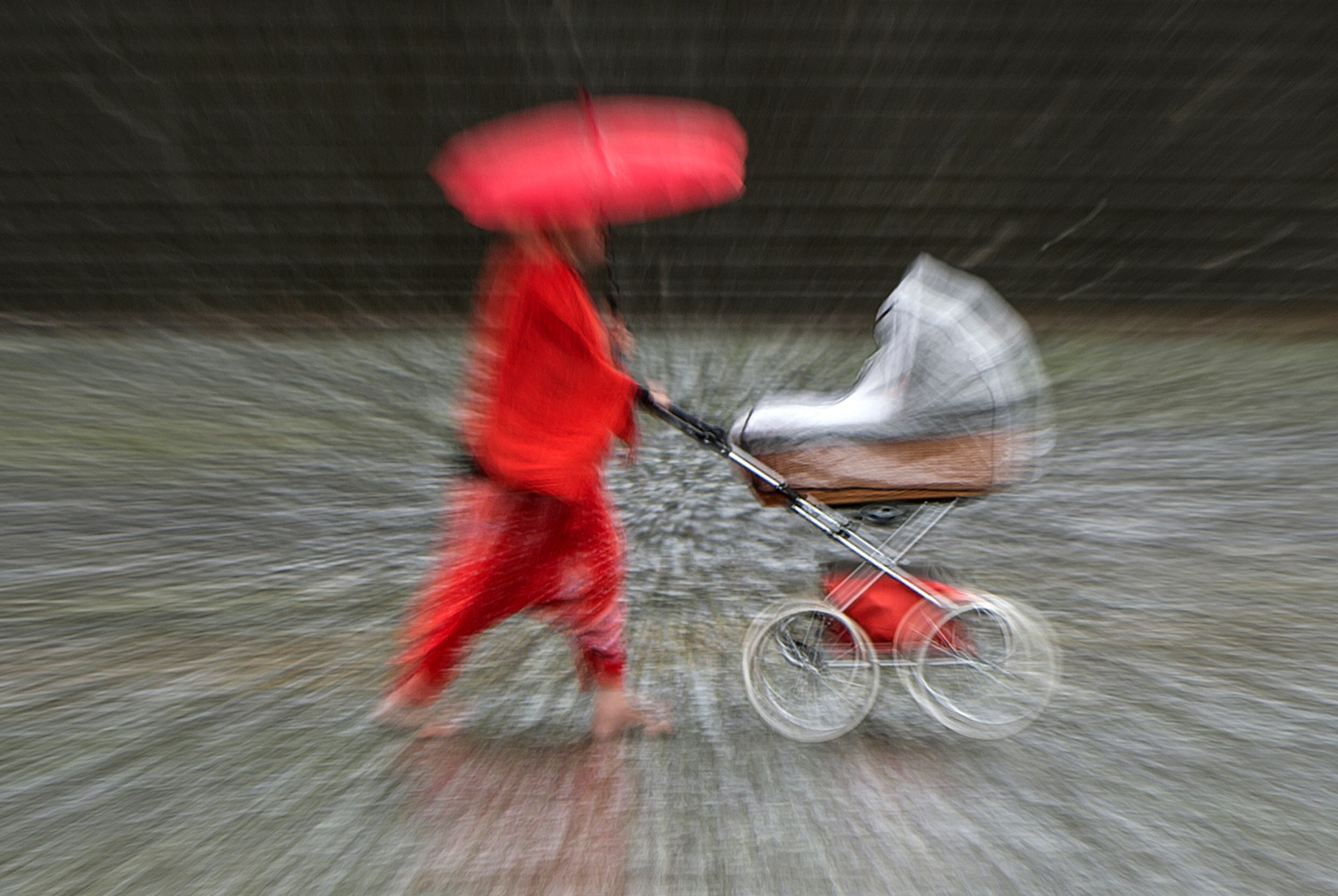 In this zoomed and long time exposure picture a woman walks with her buggy during heavy rain in Erfurt, Germany, Thursday, June 29, 2017. Weather forecasts predict changeable weather conditions in Germany for the upcoming day. (AP Photo/Jens Meyer)