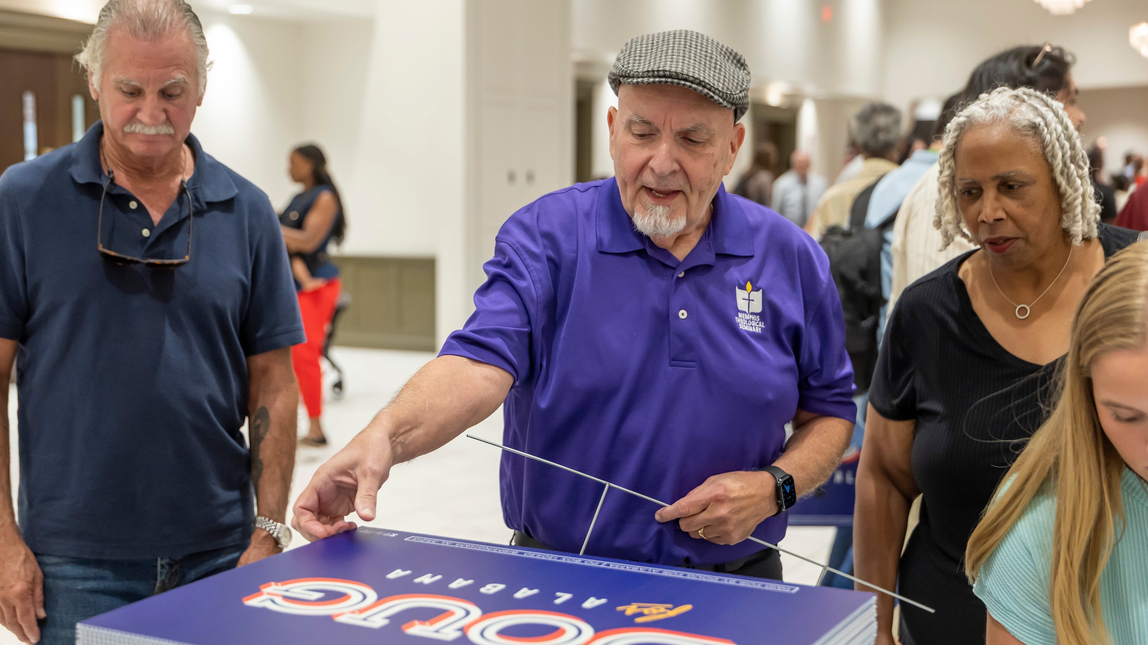 FILE - Michael Davis, of Bellwood, Ala., picks up a sign supporting Doug Jones for governor after a town hall hosted by Troy University College Democrats and the Pike County Democrats, Aug. 18, 2026, in Troy, Ala. (AP Photo/Vasha Hunt, File)