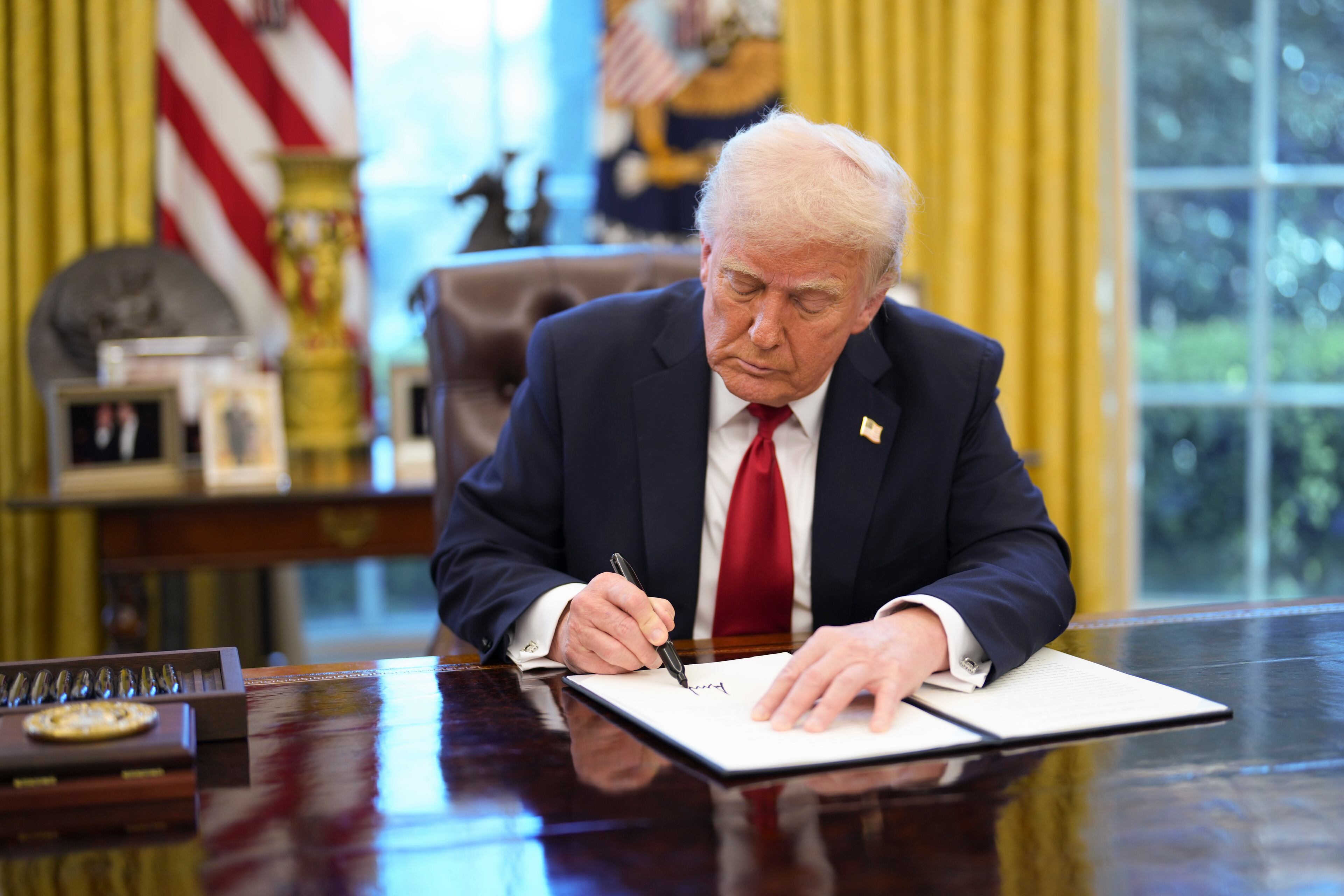 President Donald Trump signs new automotive tariffs in the Oval Office of the White House in Washington, on Wednesday, March 26, 2025. The president announced tariffs on imported cars on Wednesday, a measure that could bring car factories to the United States but raise prices for consumers. (Doug Mills/The New York Times)