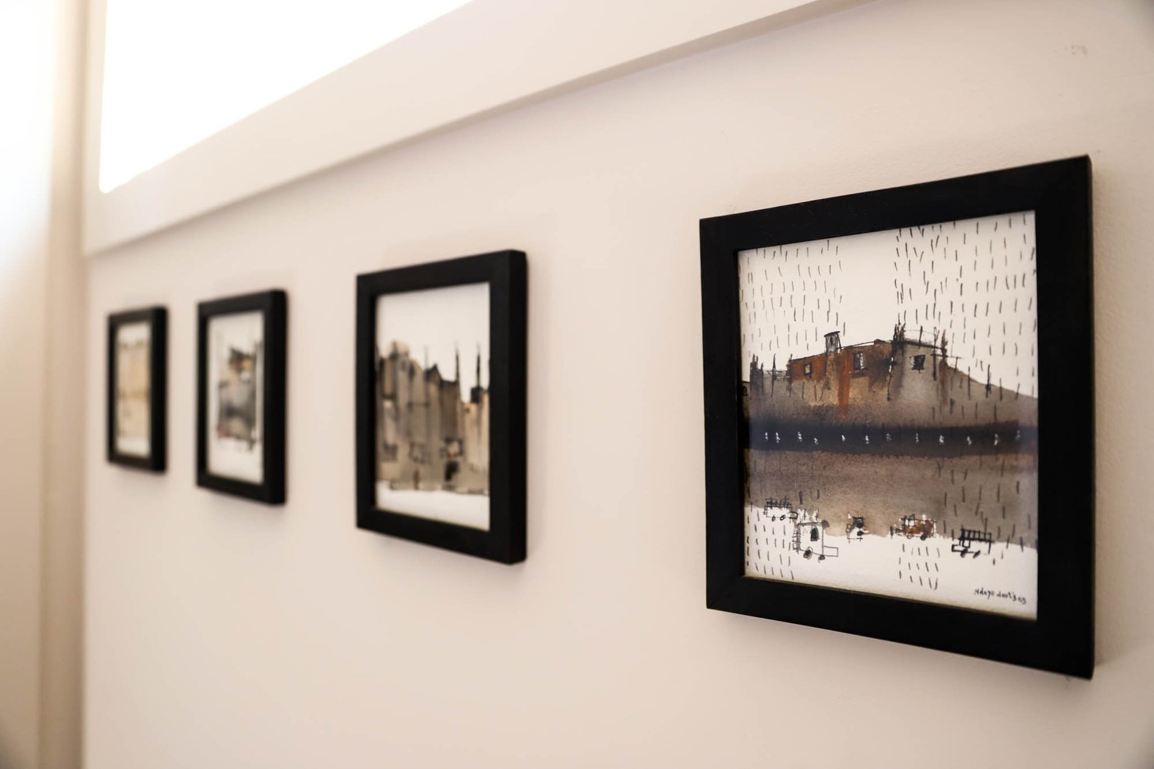 A row of four watercolors by Senegalese artist Ndouts Ndoye, depcting Dakar, Senegal, hangs in Anja and Jumbe Sebunya's Old Fourth Ward home. Their home will be featured on the Old Fourth Ward Tour of Homes on September 22, 2019. Text by Shannon Dominy. Photo by Reynolds Rogers.