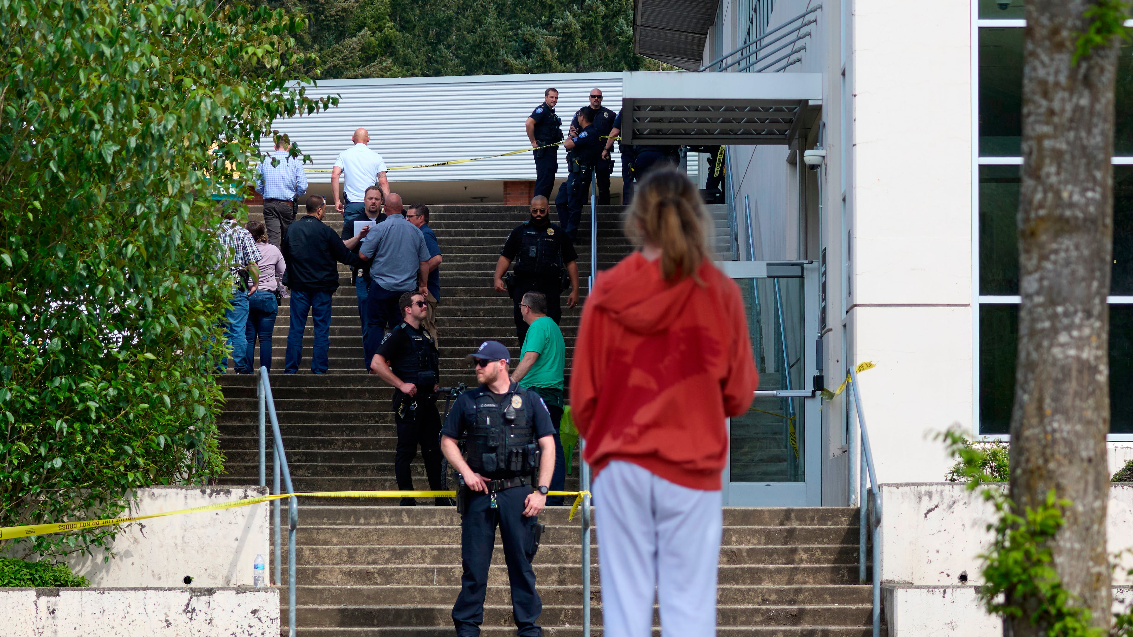A student watches as Tacoma Police officers investigate after multiple people were injured in a stabbing at Foss High School, Thursday, April 30, 2026, in Tacoma, Wash. (AP Photo/John Froschauer)