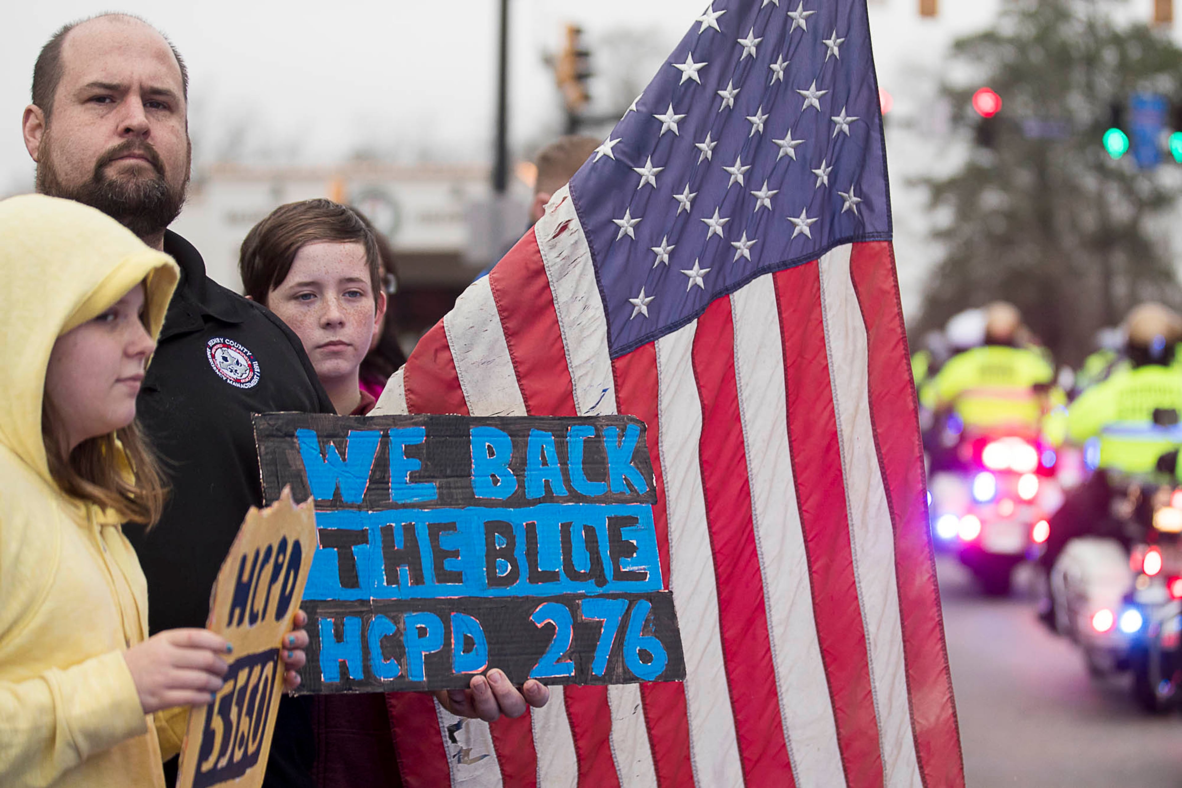 01/03/2019 -- McDonough, Georgia -- Supporters display signs of support for police officers as the funeral procession for slain Henry County Police Officer Michael Smith travels through McDonough Squared in McDonough, Thursday, January 3, 2019. Henry County police Officer Michael Smith died from injuries from a gunshot wound he received while responding to a report of a irate man at a McDonough-area dental office. (ALYSSA POINTER/ALYSSA.POINTER@AJC.COM)