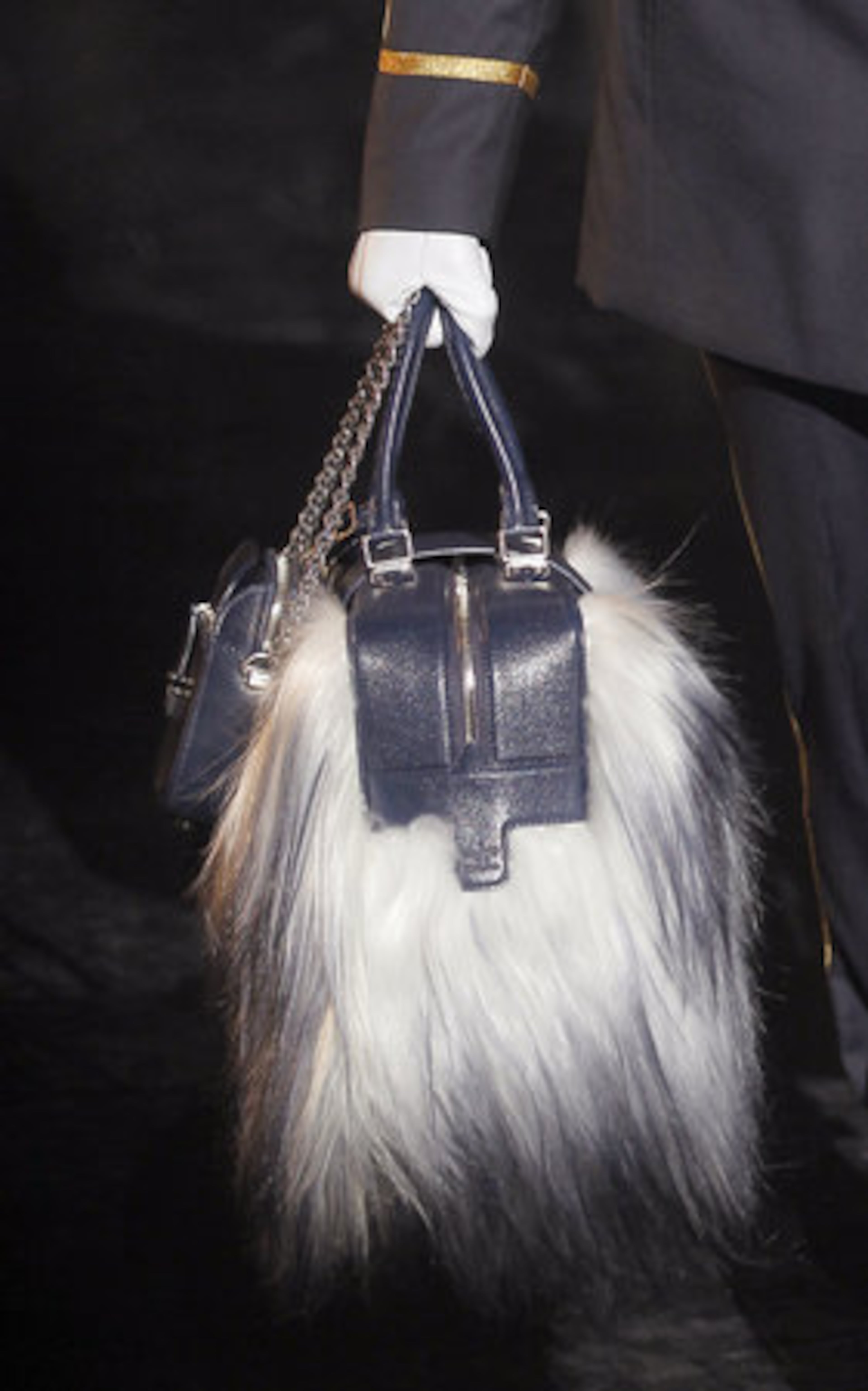 A furry bag hangs from a model's hand on the Louis Vuitton runway.